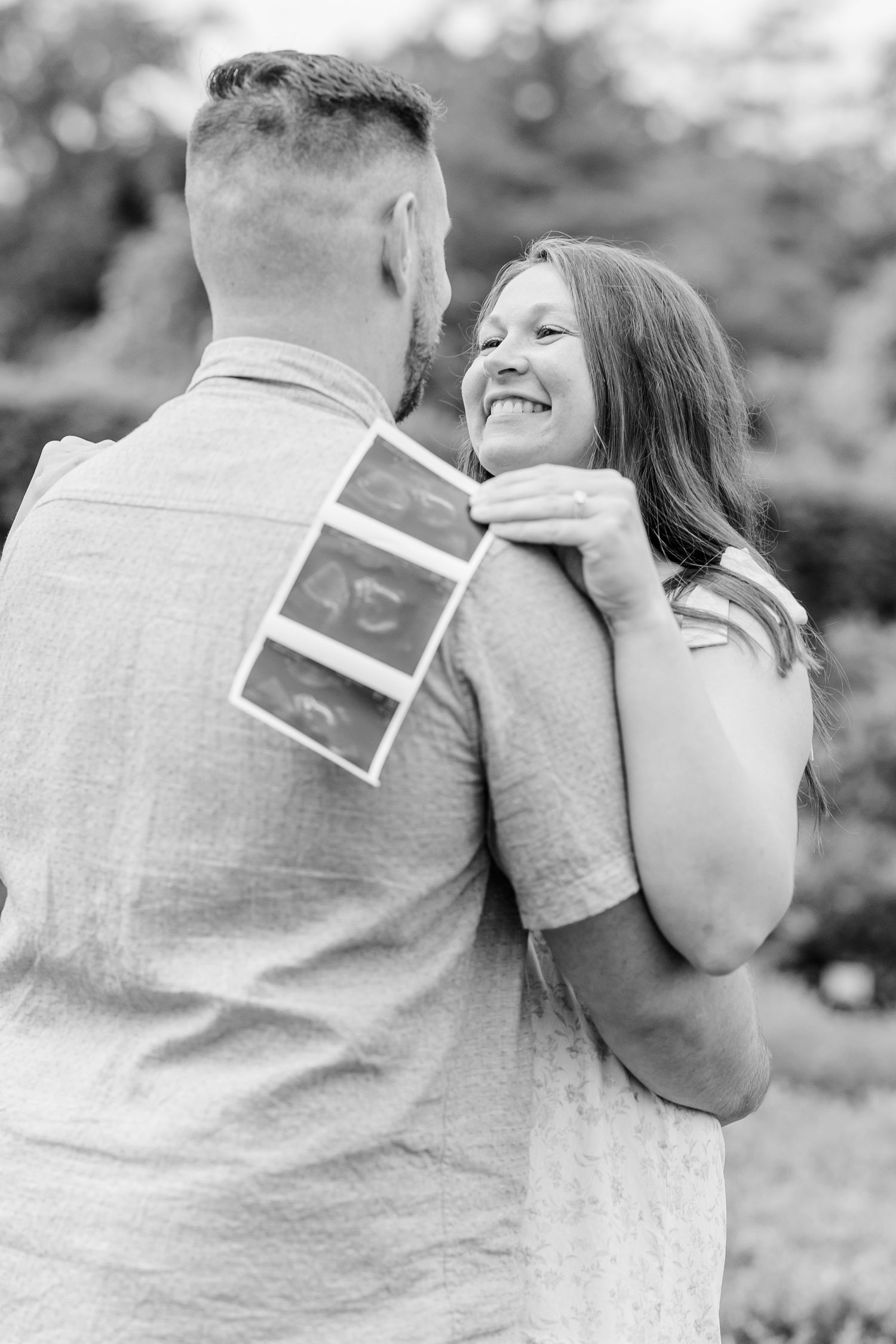 Black and white maternity photo of expecting parents holding ultrasound photos