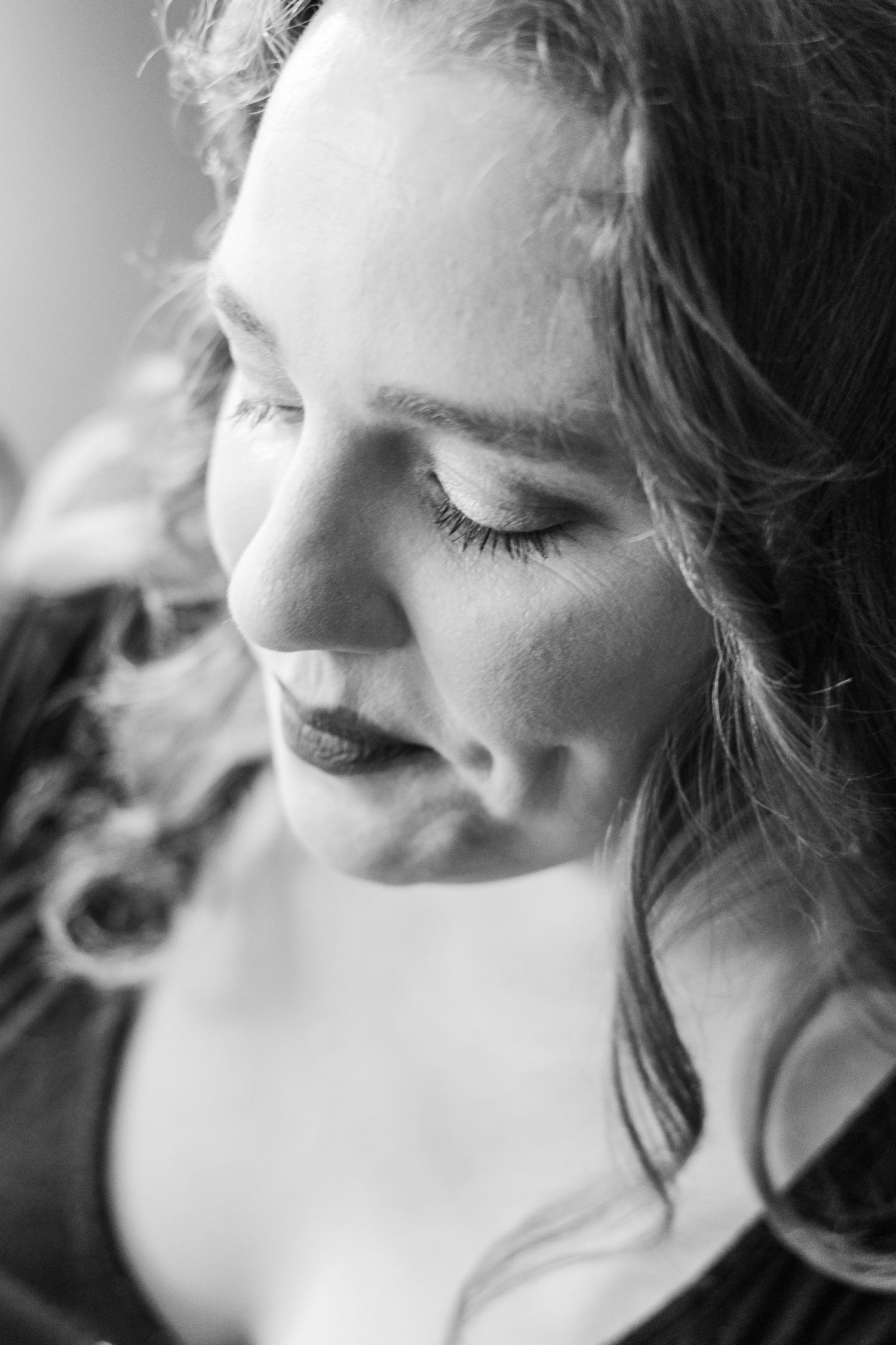 Black and white portrait of a woman in profile with curled hair and closed eyes.