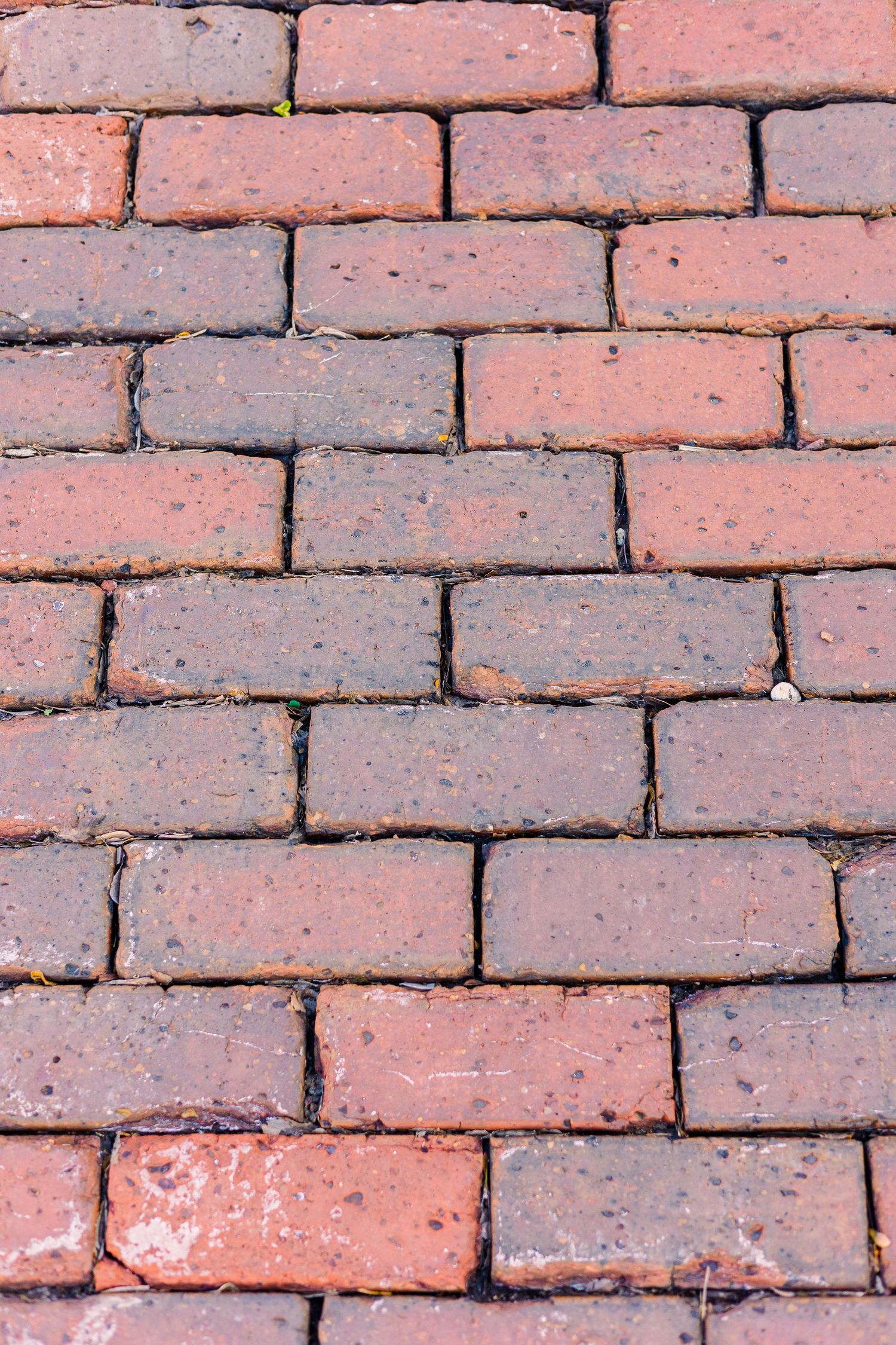 Close-up texture of weathered red brick pavers in geometric pattern.
