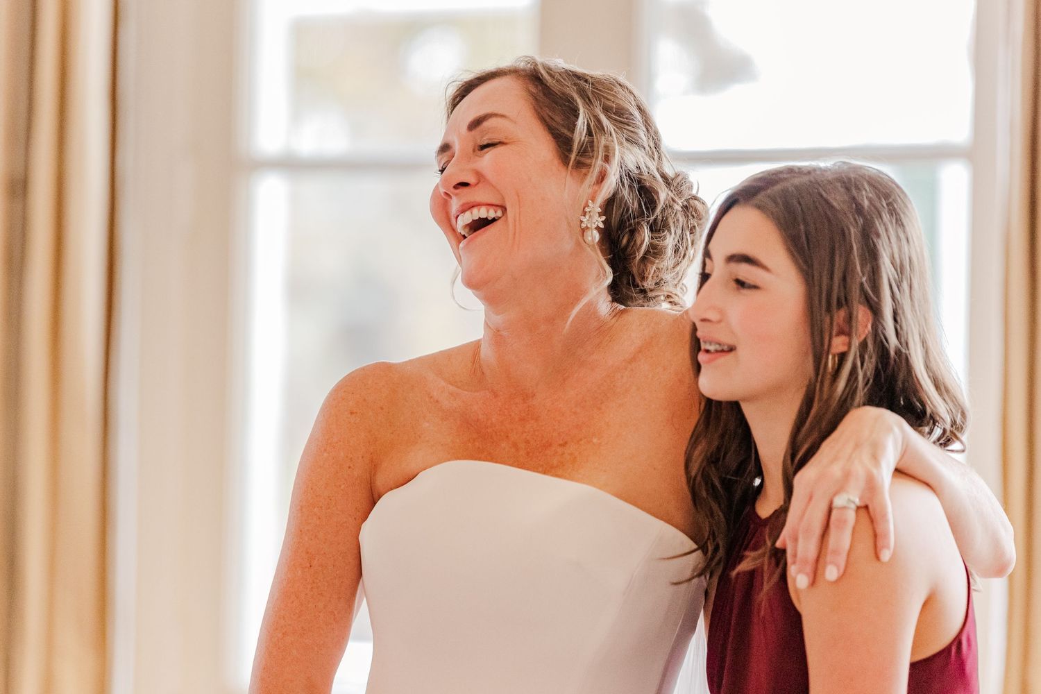 Two people sharing a joyful moment of laughter at a formal event.
