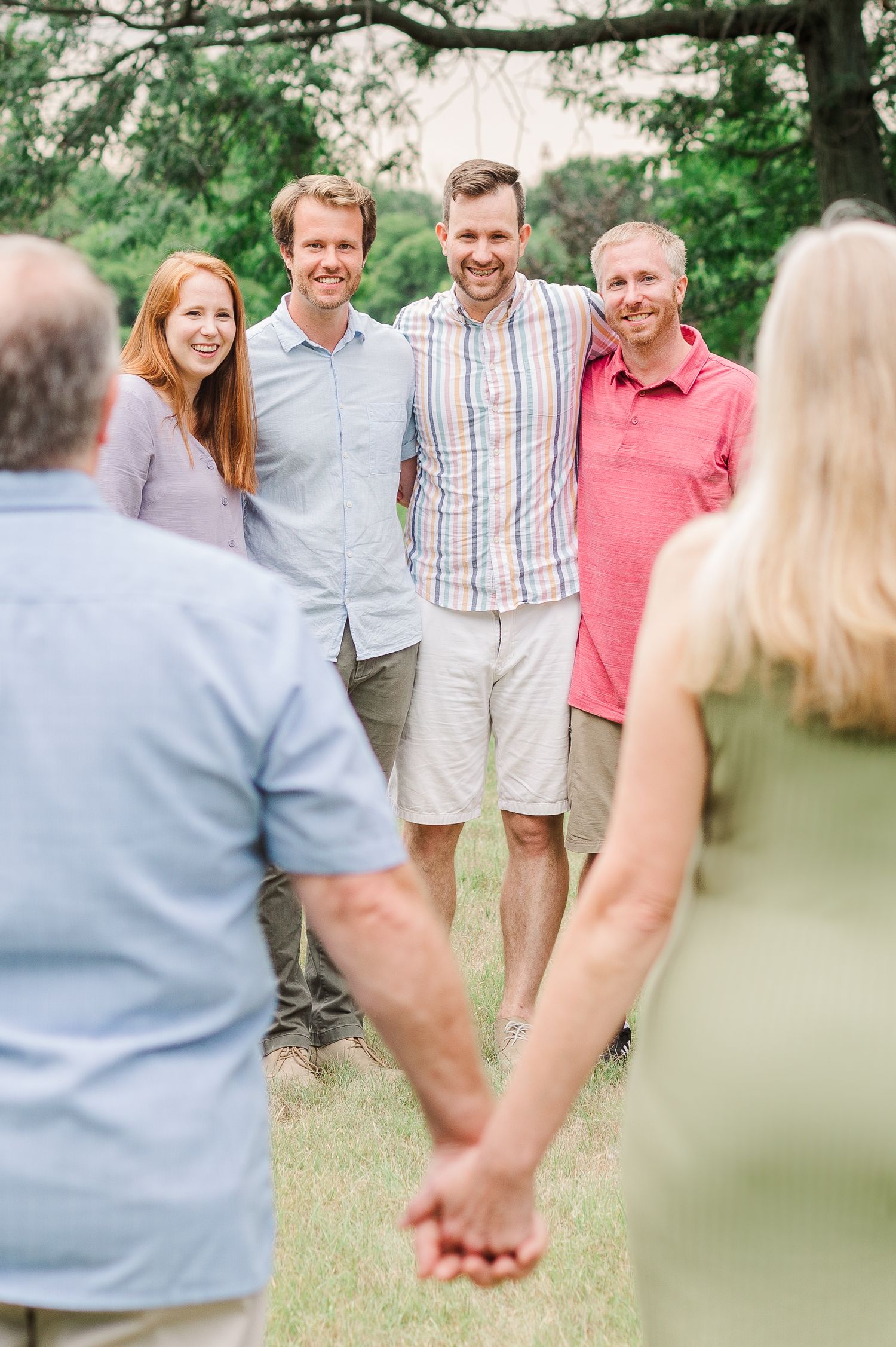 A group of friends posing and laughing together outdoors on a sunny summer day.