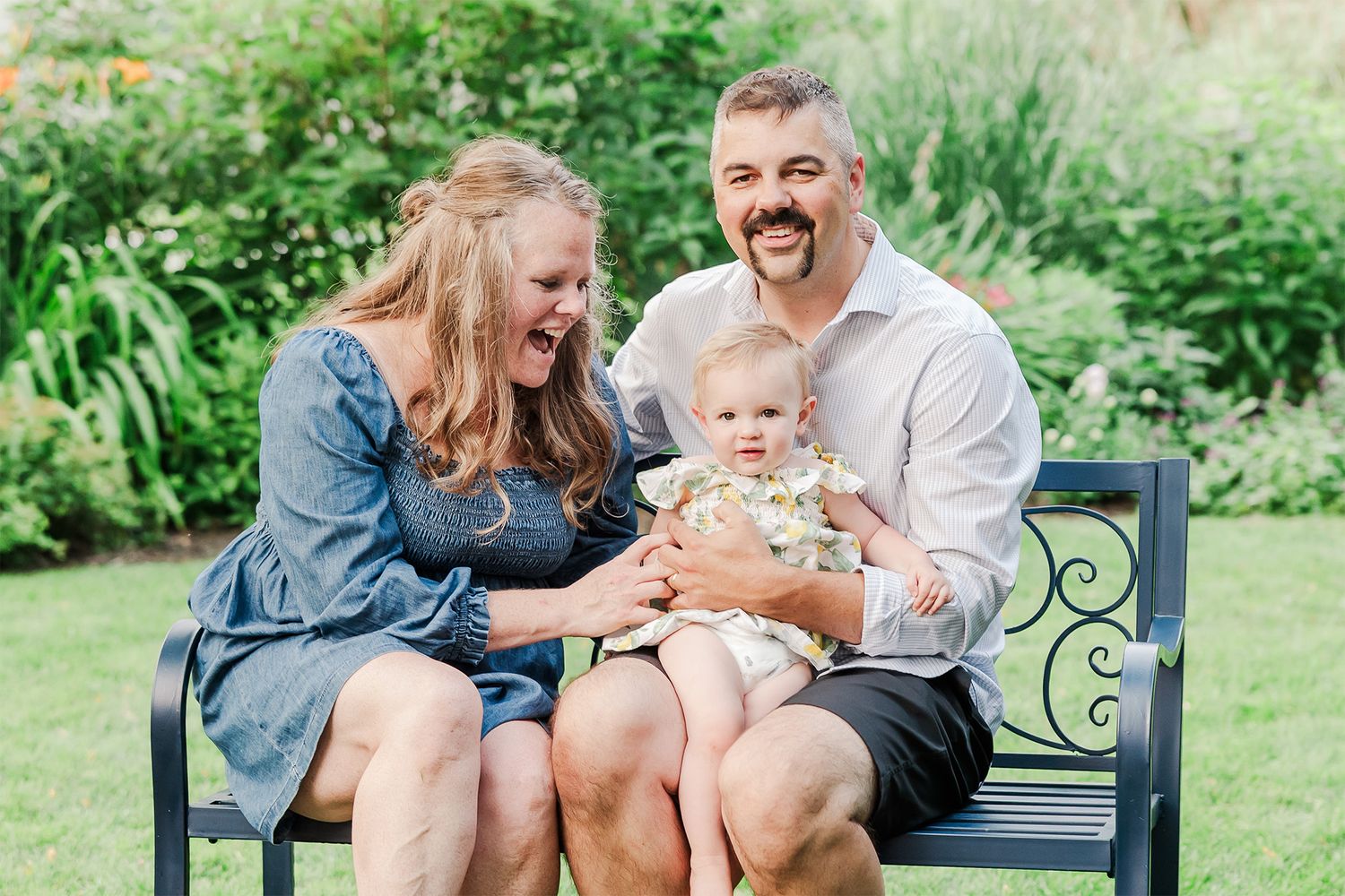 A joyful family moment captured on a decorative garden bench surrounded by lush greenery.