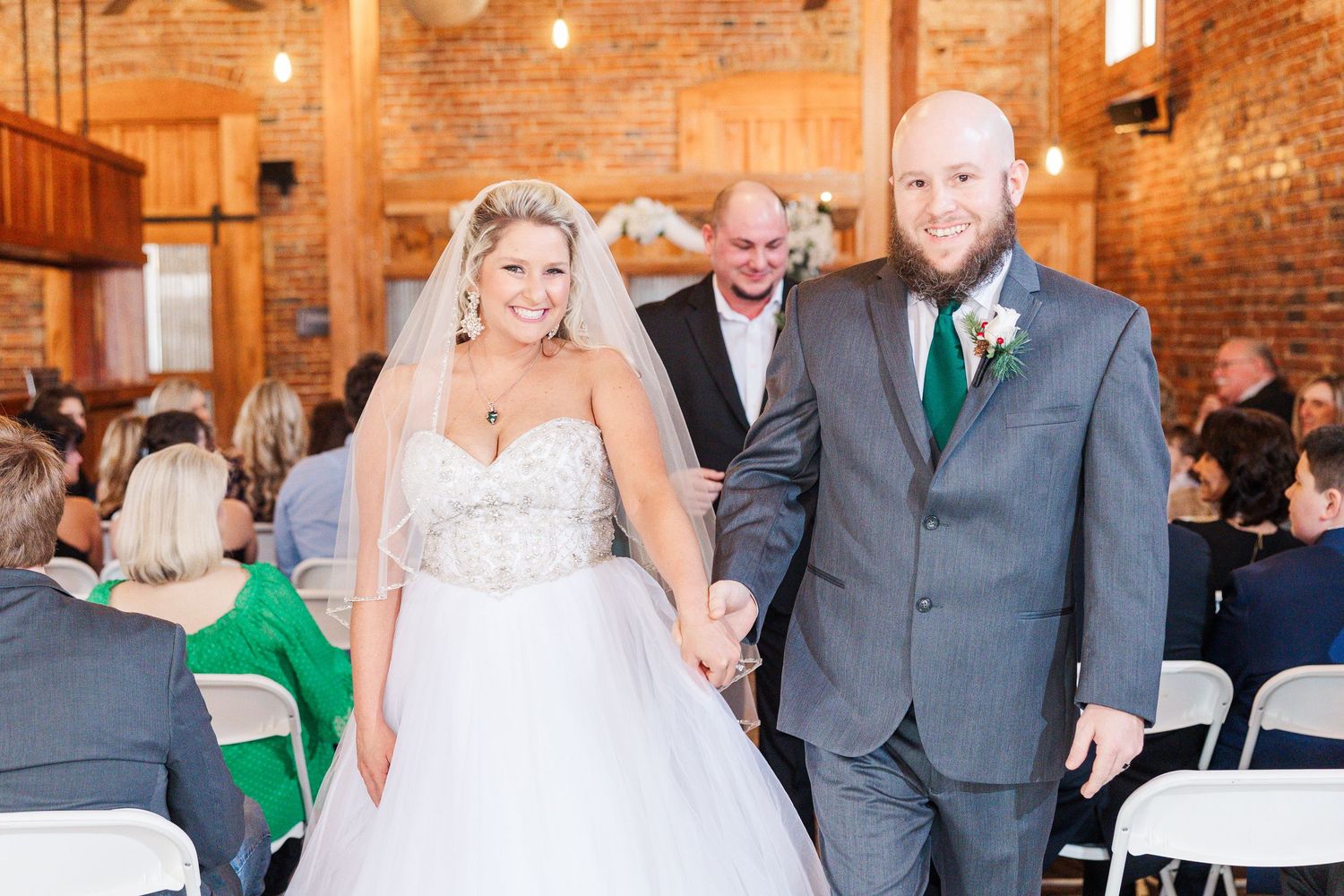 Wedding ceremony celebration in a rustic brick venue with guests seated in folding chairs.