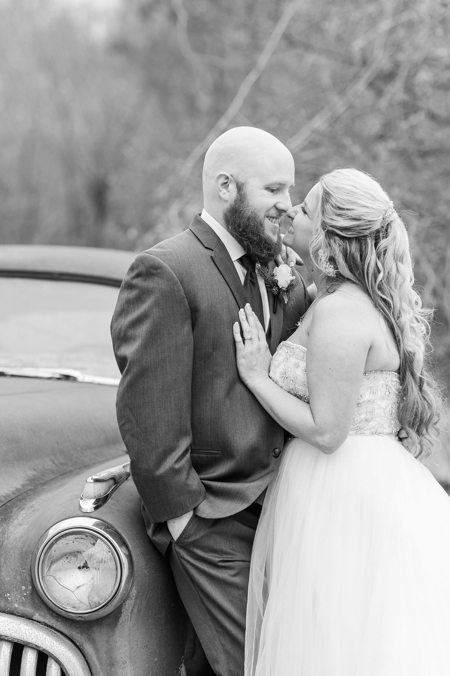 Romantic wedding portrait in black and white featuring a vintage car headlight and fender.