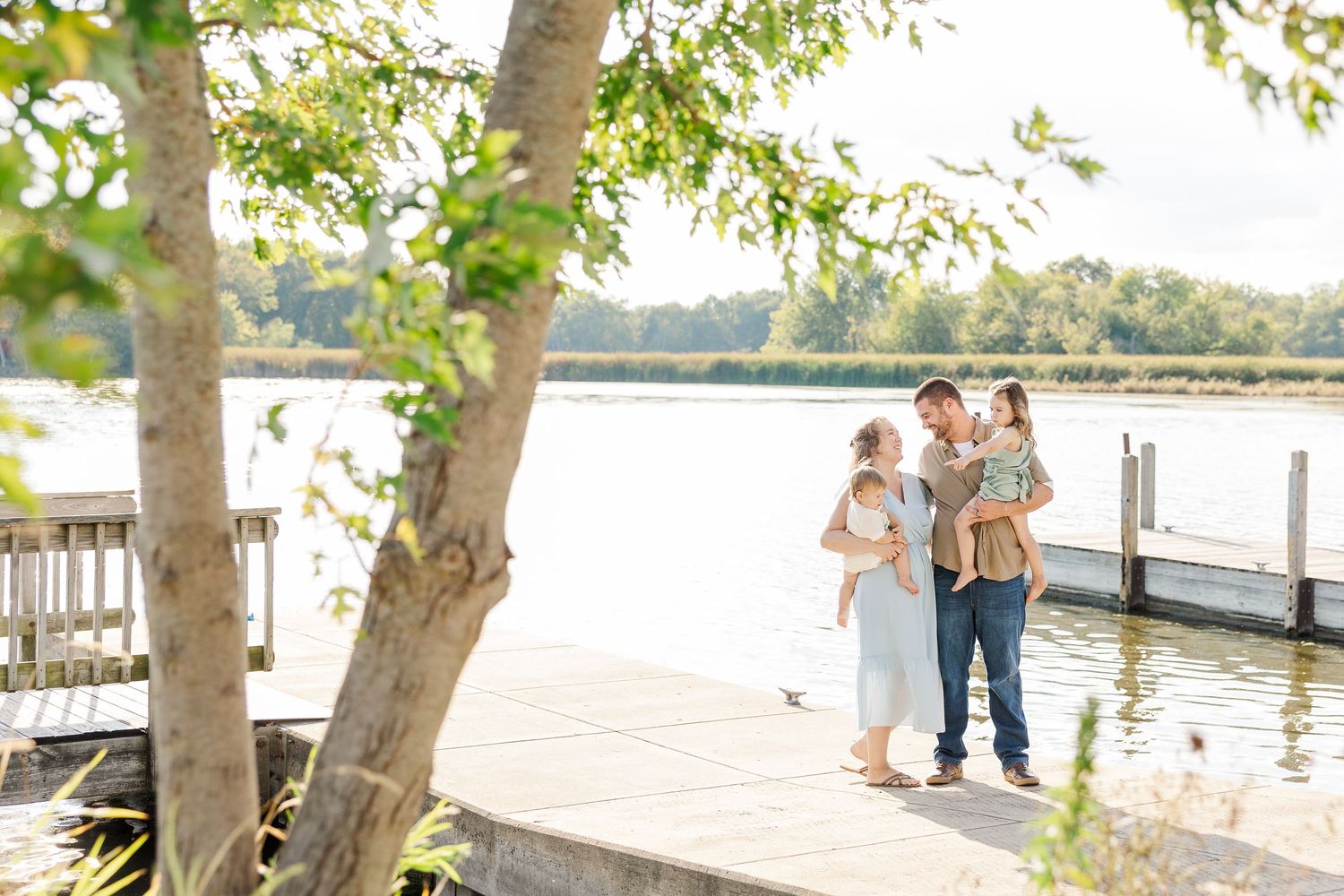 People enjoy a peaceful afternoon stroll along a tree-lined waterfront path on a sunny day.