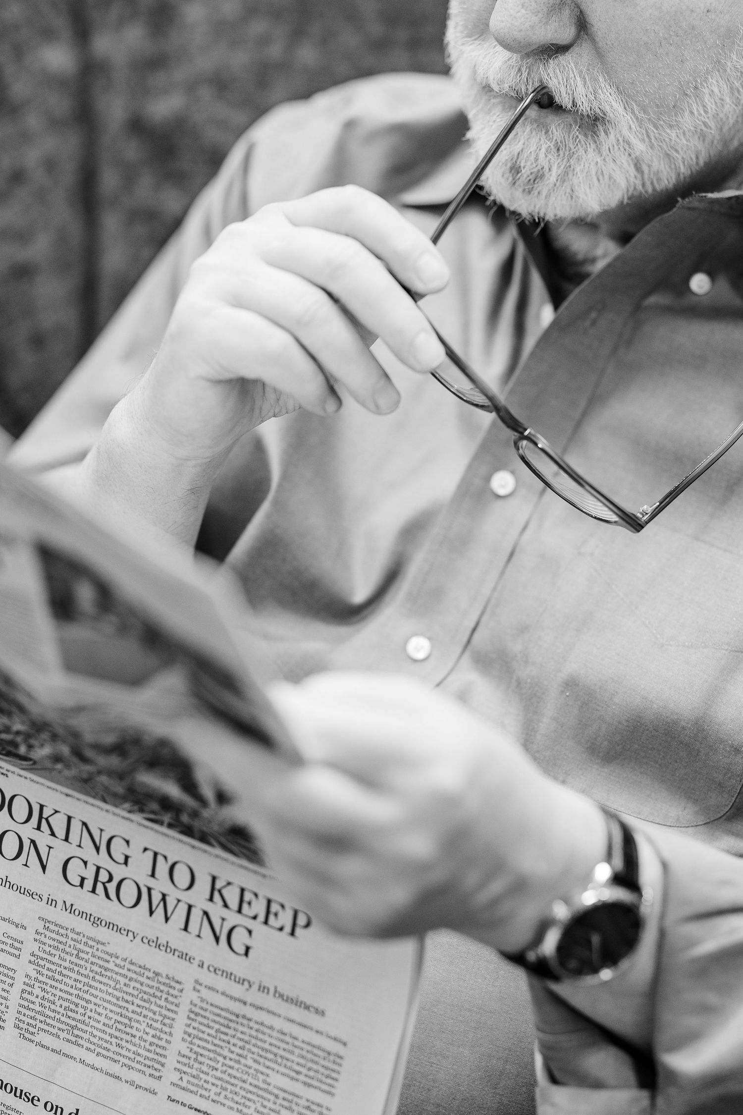 Black and white Beacon Hill senior living branding photo in Lombard, Illinois featuring resident with newspaper and glasses