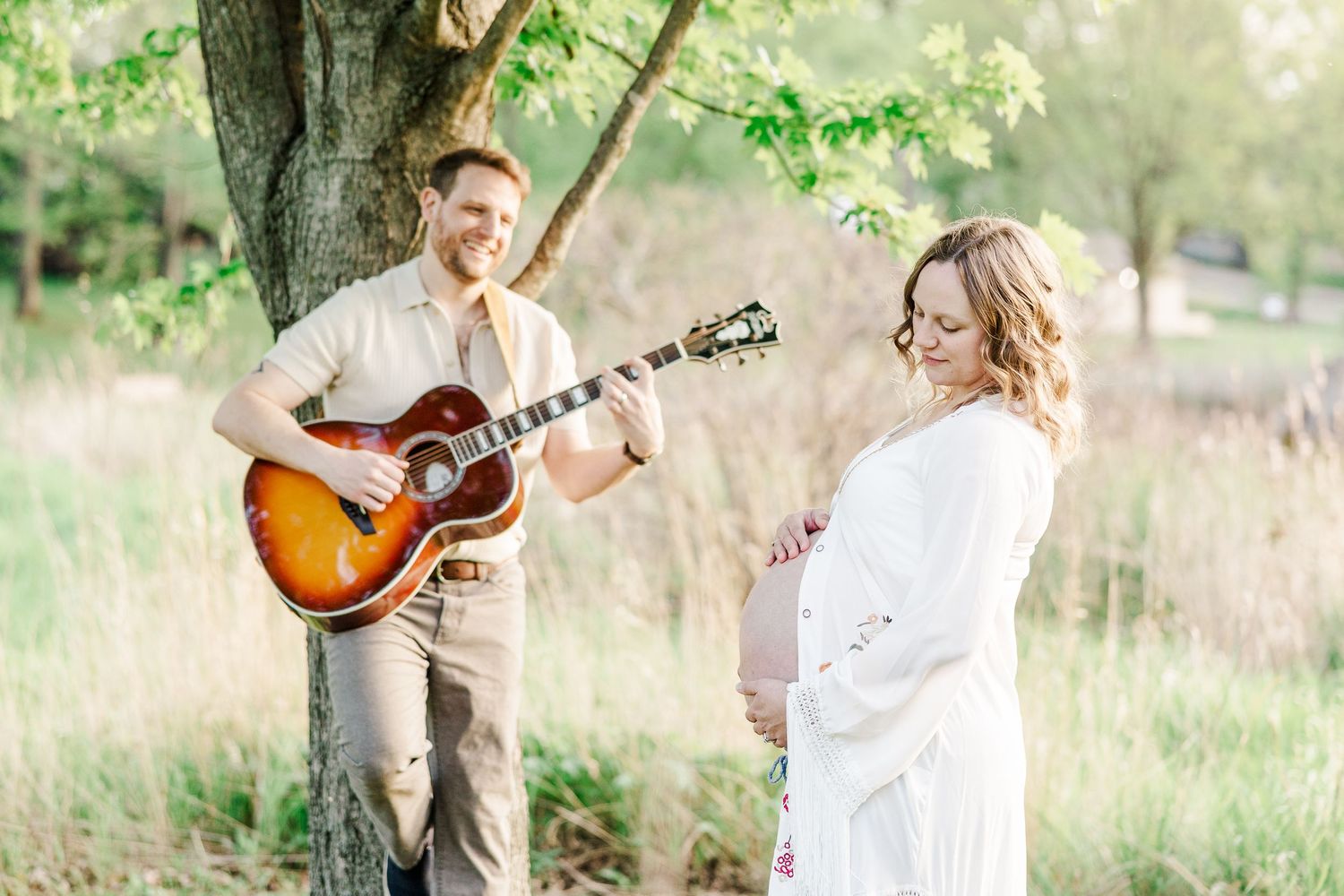Father playing guitar for mother during a music-inspired maternity session at Veterans Acres.