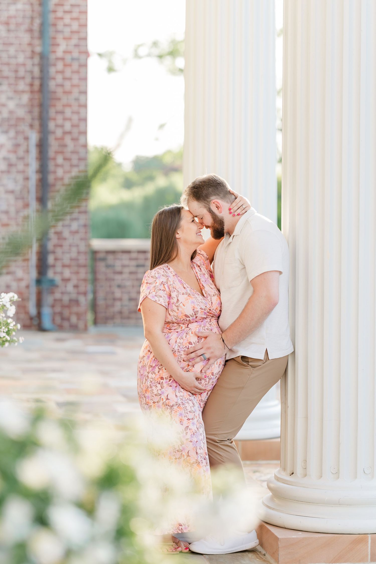 Expecting parents sharing a kiss by white columns during their Cantigny Park maternity session in Wheaton