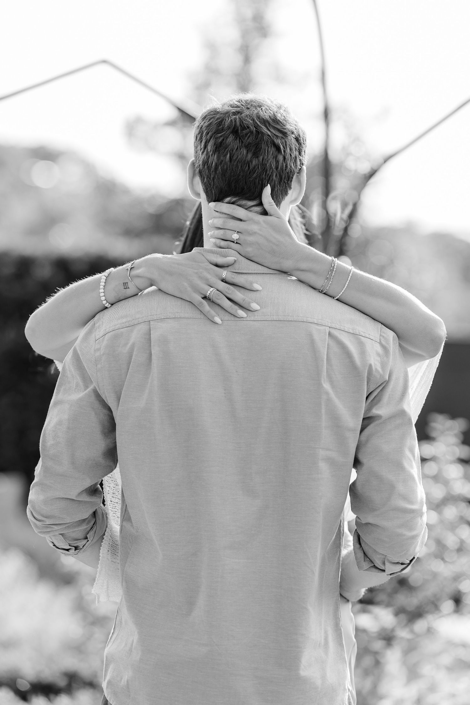 Black-and-white portrait of Alysia wrapping her arms around Jack after their proposal.