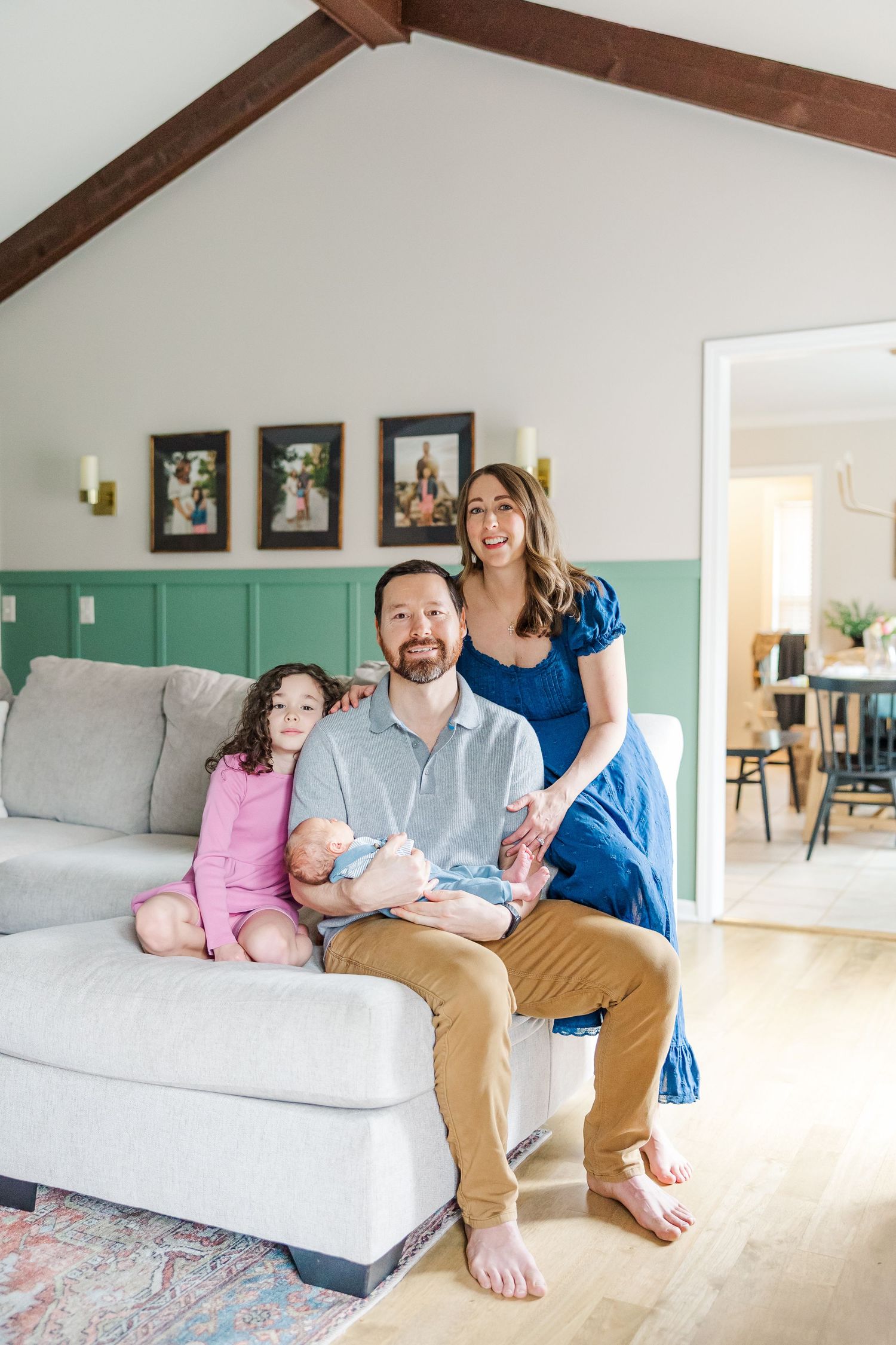 Family of four together on couch during bright in-home lifestyle newborn session in Crystal Lake, Illinois