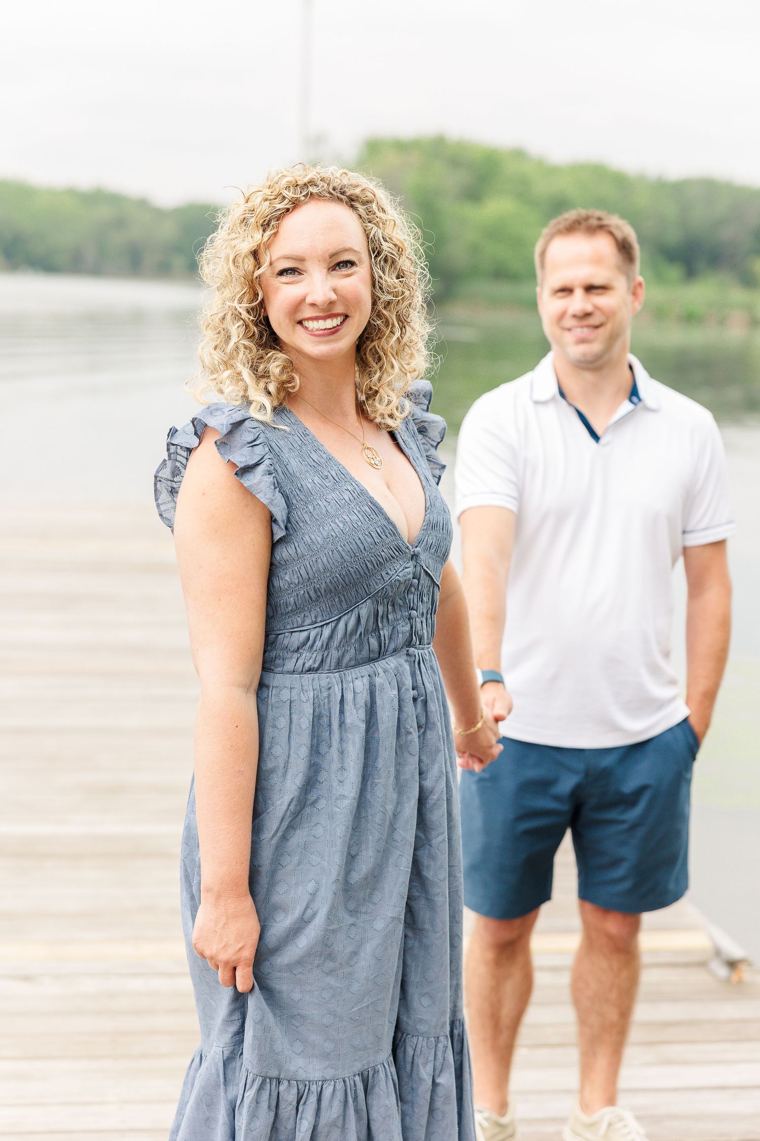 A couple shares a tender moment on a wooden dock by the lake.