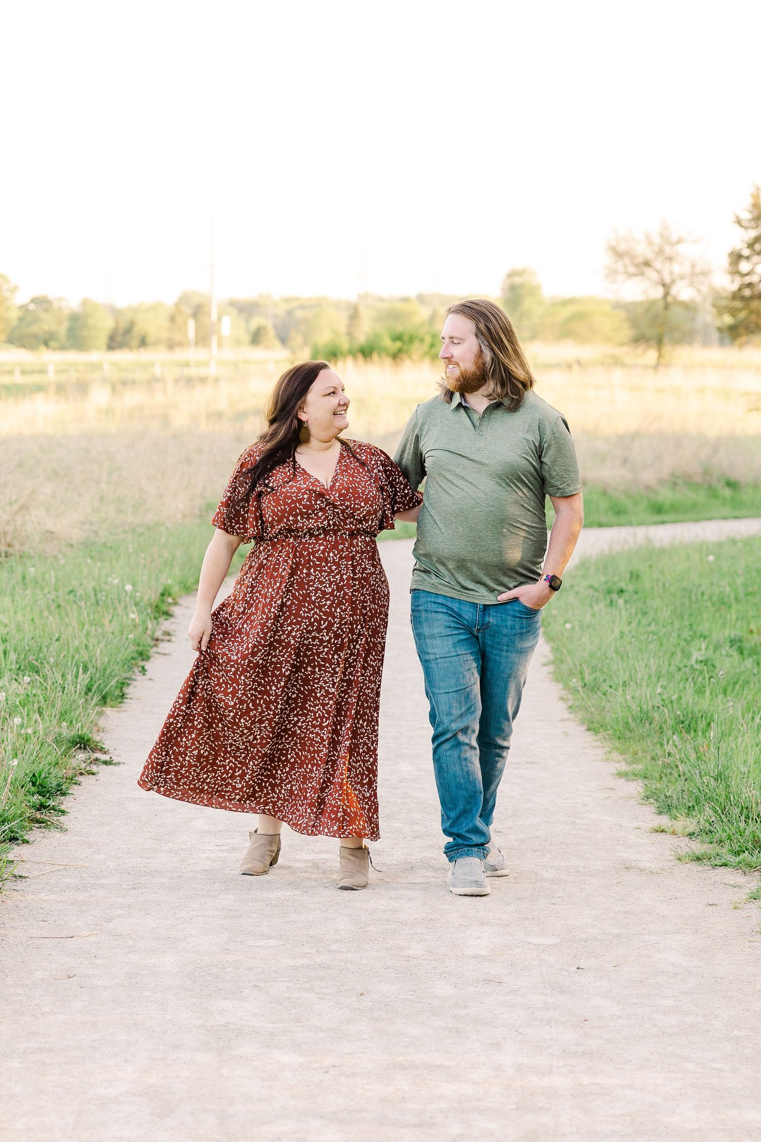 A couple walks together on a dirt path enjoying a tender moment in nature.