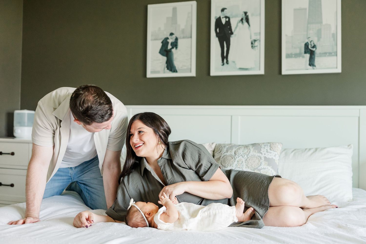 Parents relaxing on the bed with newborn baby girl during an in-home lifestyle newborn session