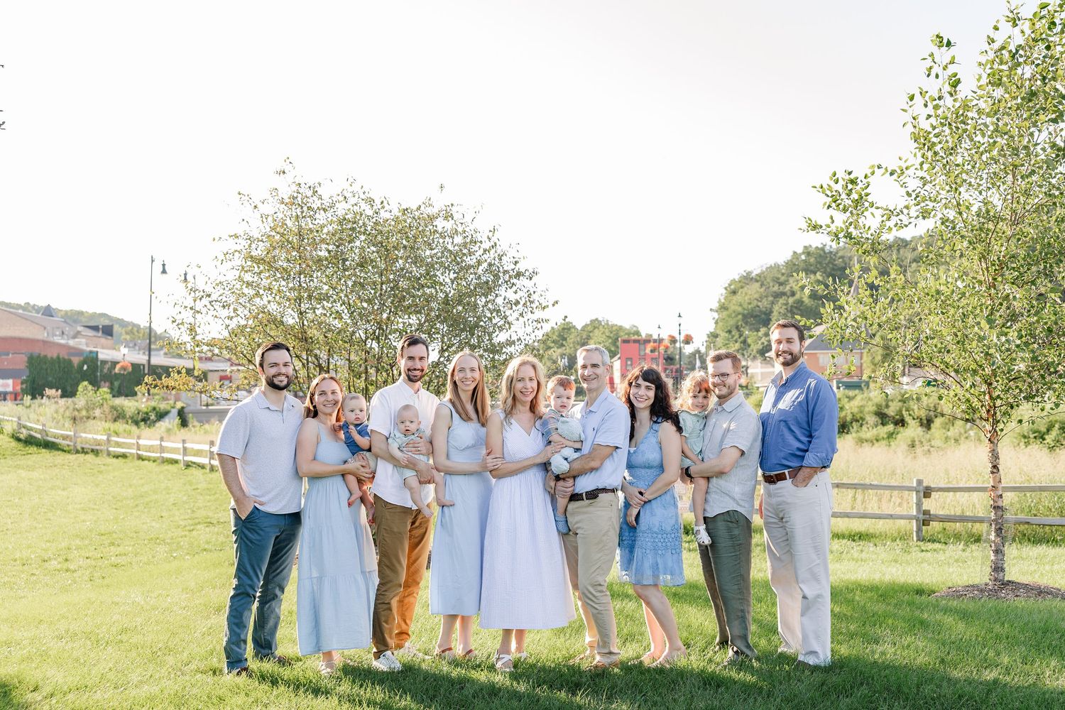 Large family group smiling together outdoors on a sunny day in a park.