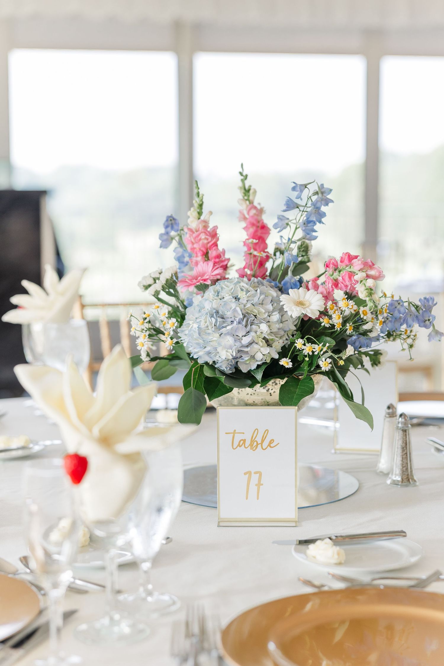 Elegant wedding table centerpiece with pink and blue flowers beside Table 77 number card.