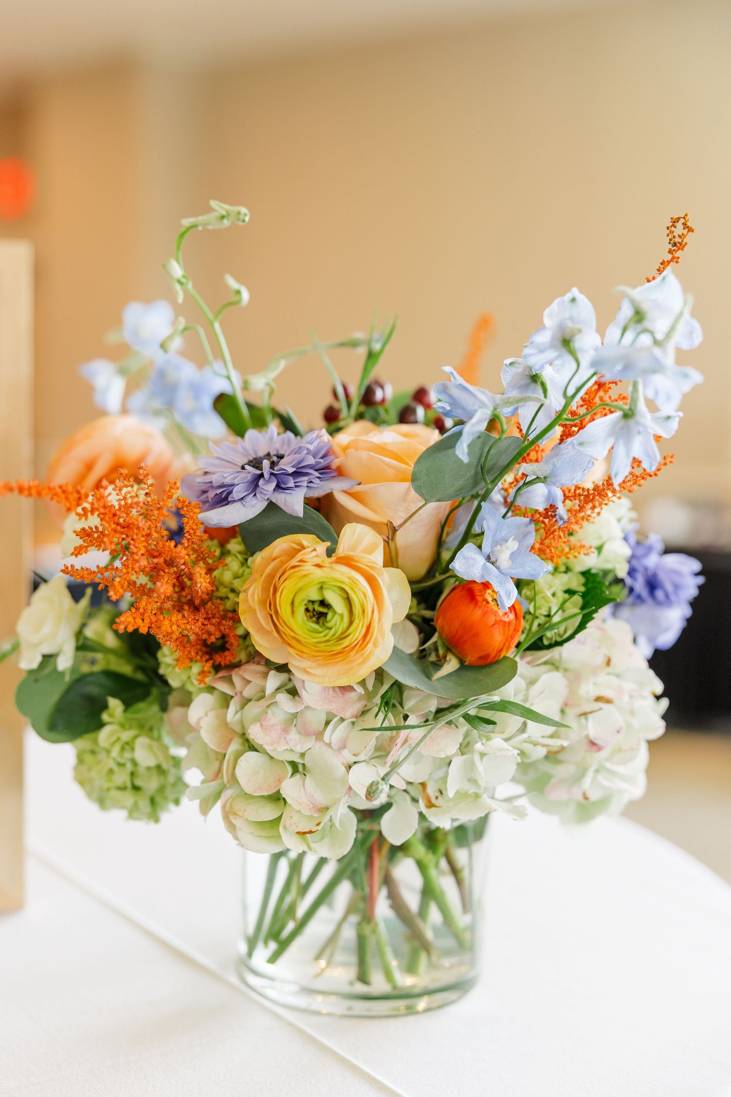 Wildflower bouquet with orange ranunculus and blue delphinium at Sarah's bridal shower