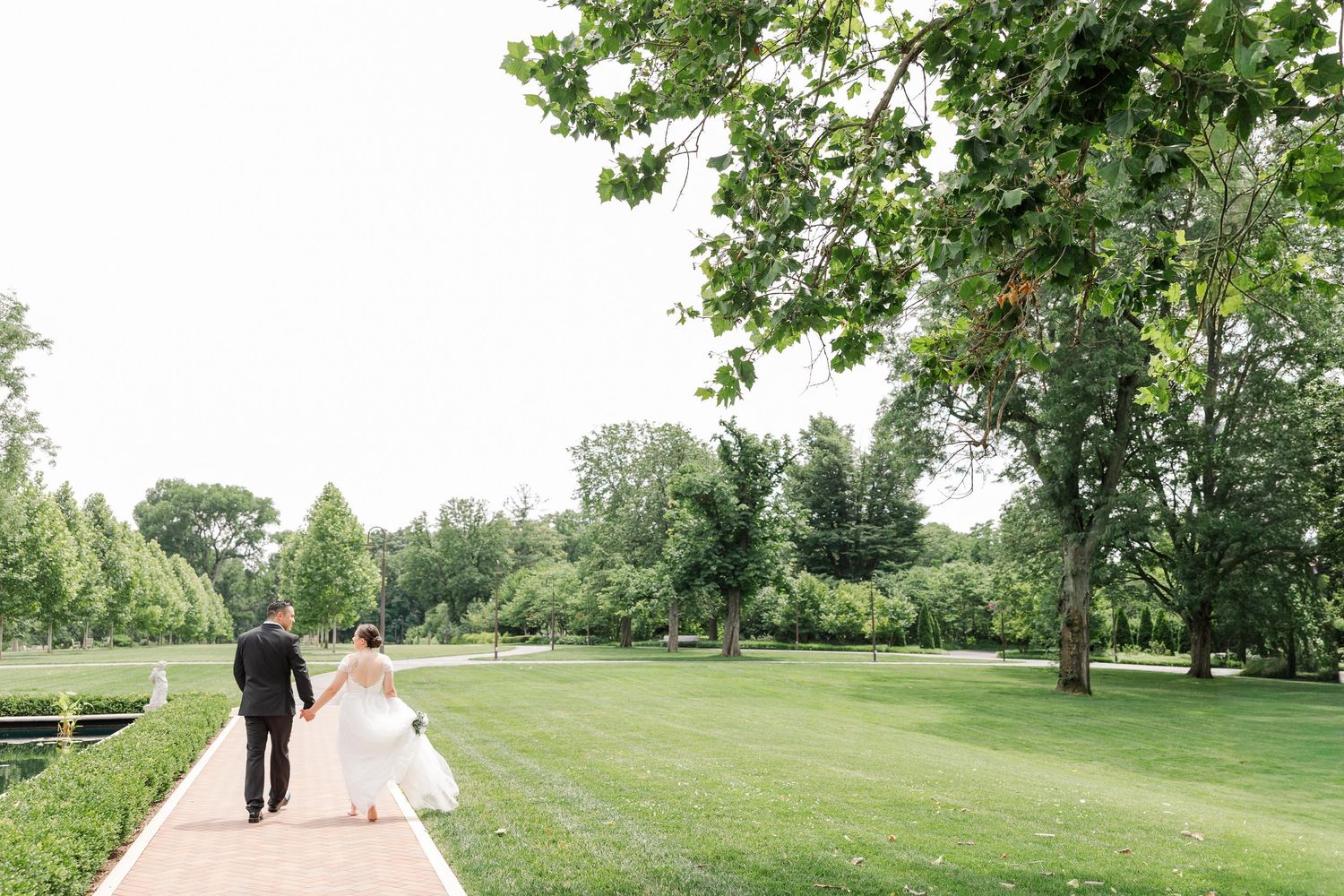 Wide portrait of Monika and Rafael walking together across the lawn at Cantigny Park.