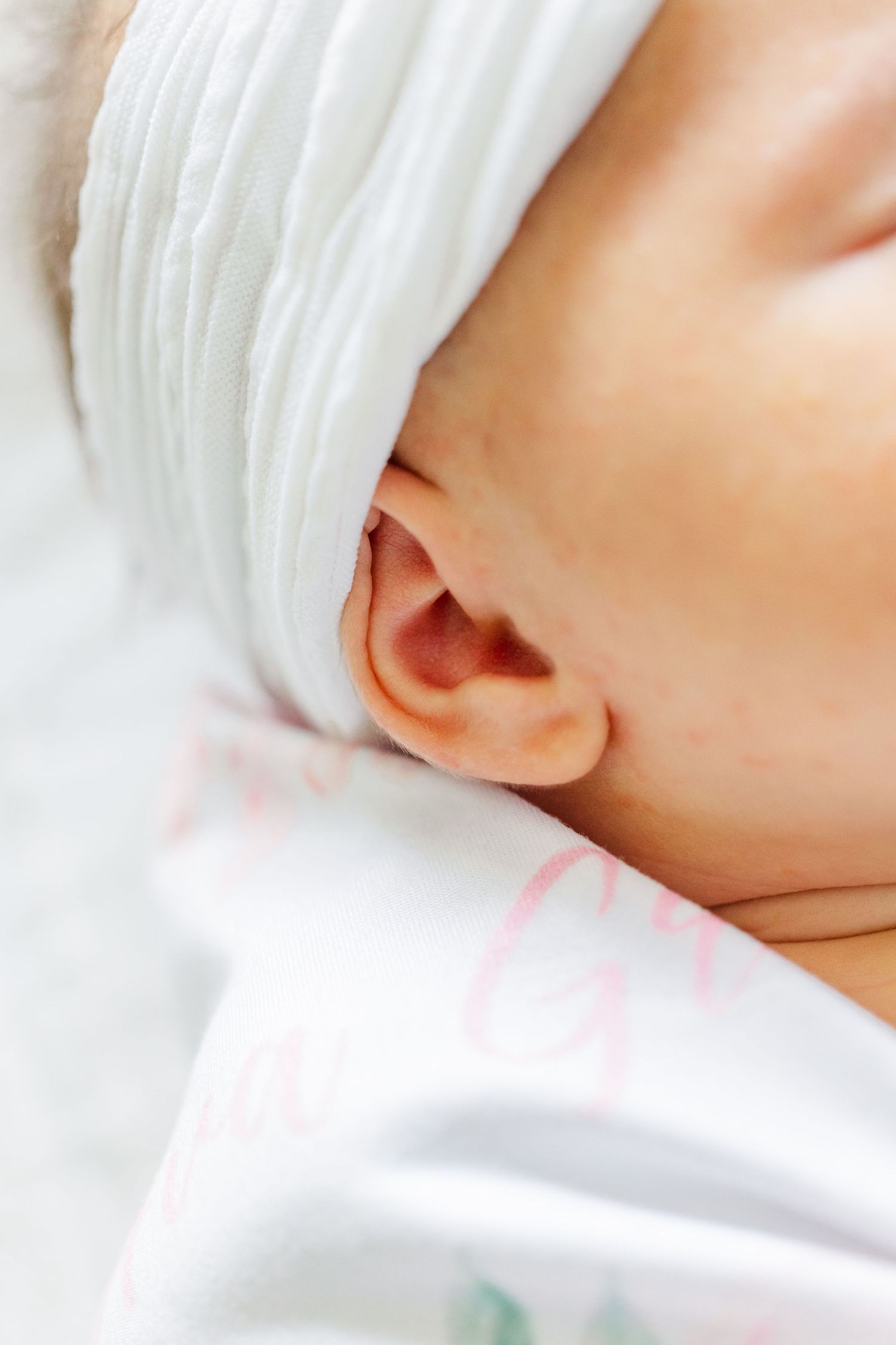 Close-up newborn detail photo of baby girl wrapped in a white swaddle during an in-home session