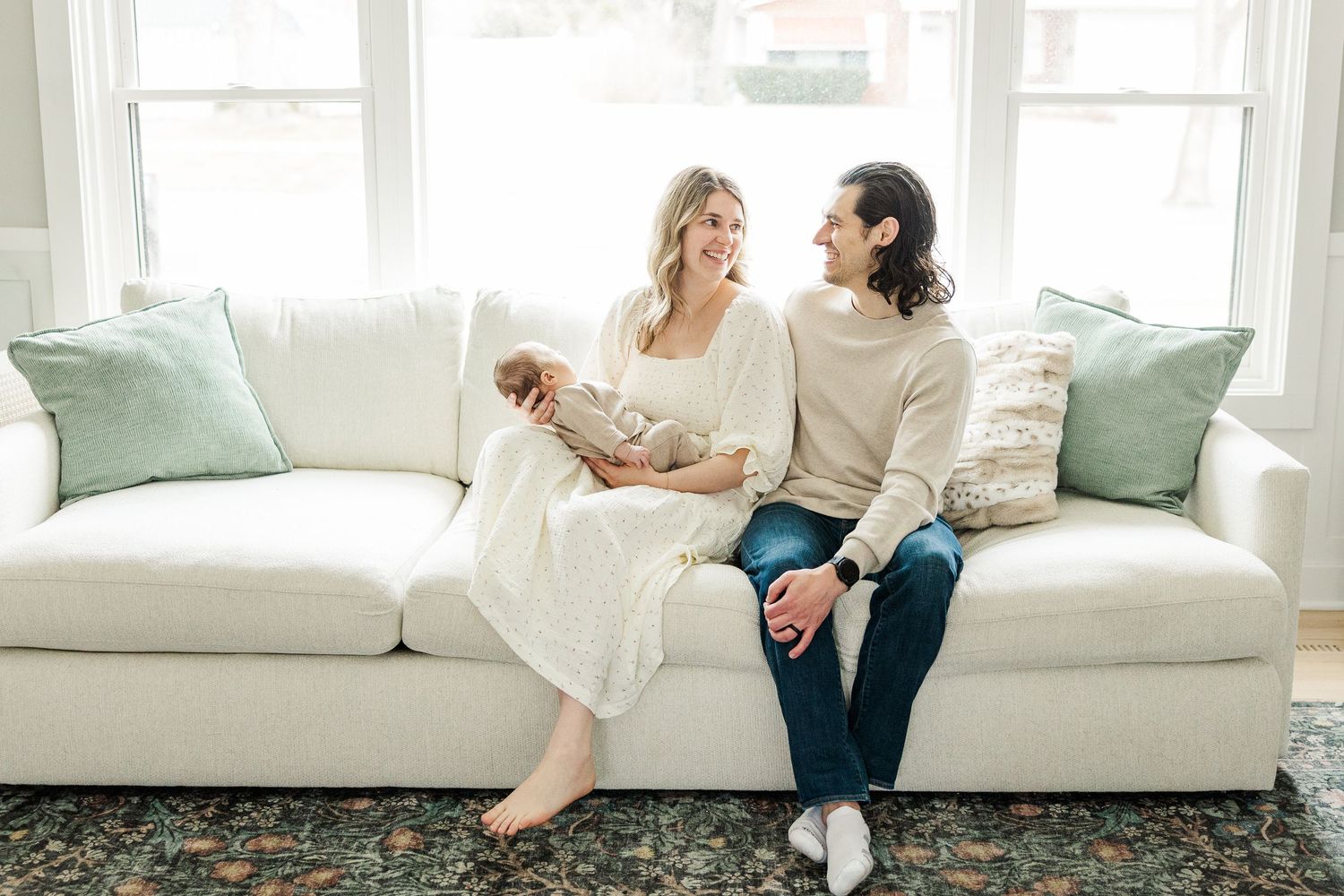 Palatine IL lifestyle newborn photographer capturing parents with their baby on a couch during a bright in-home newborn session
