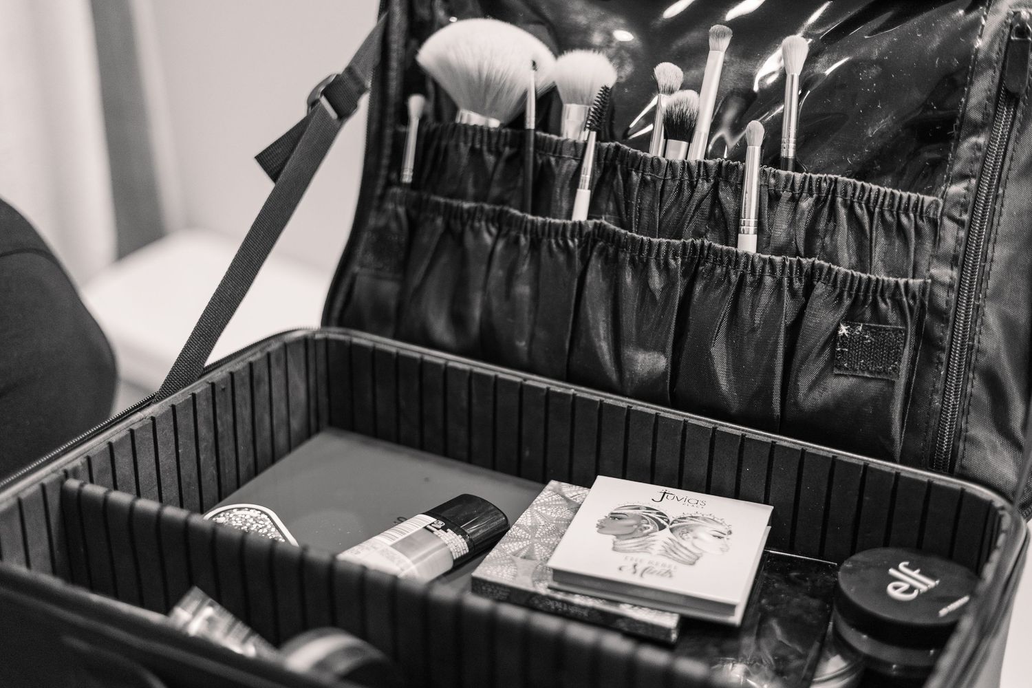 Black and white photo of an open makeup case with brushes and cosmetic tools.