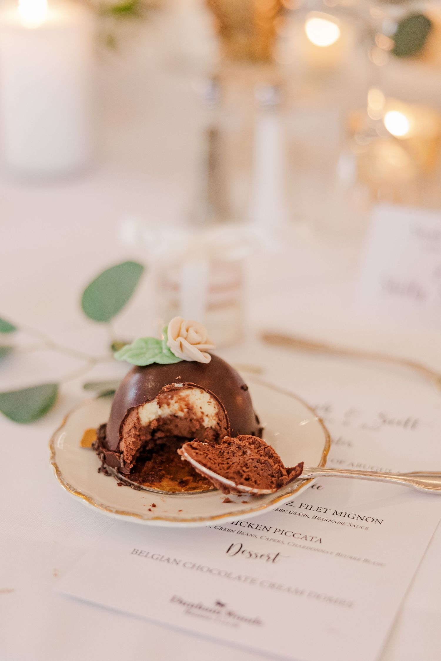 Close-up of a cut chocolate dome dessert revealing layers on an elegant place setting.