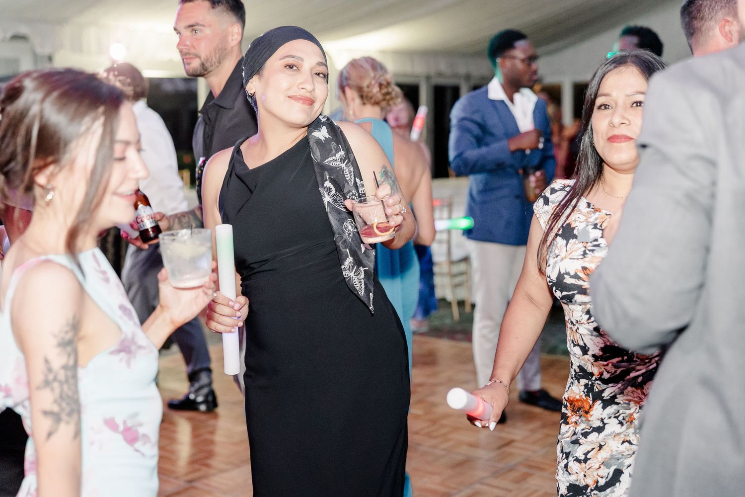 Wedding guests in formal attire socializing and dancing together inside a bright elegant reception venue.