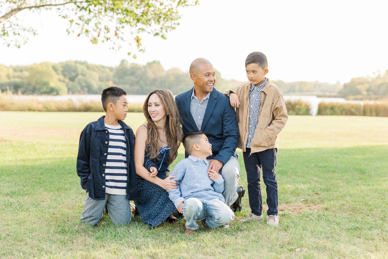 A group sits together outdoors in casual clothing on grassy field during golden hour. Busse Woods