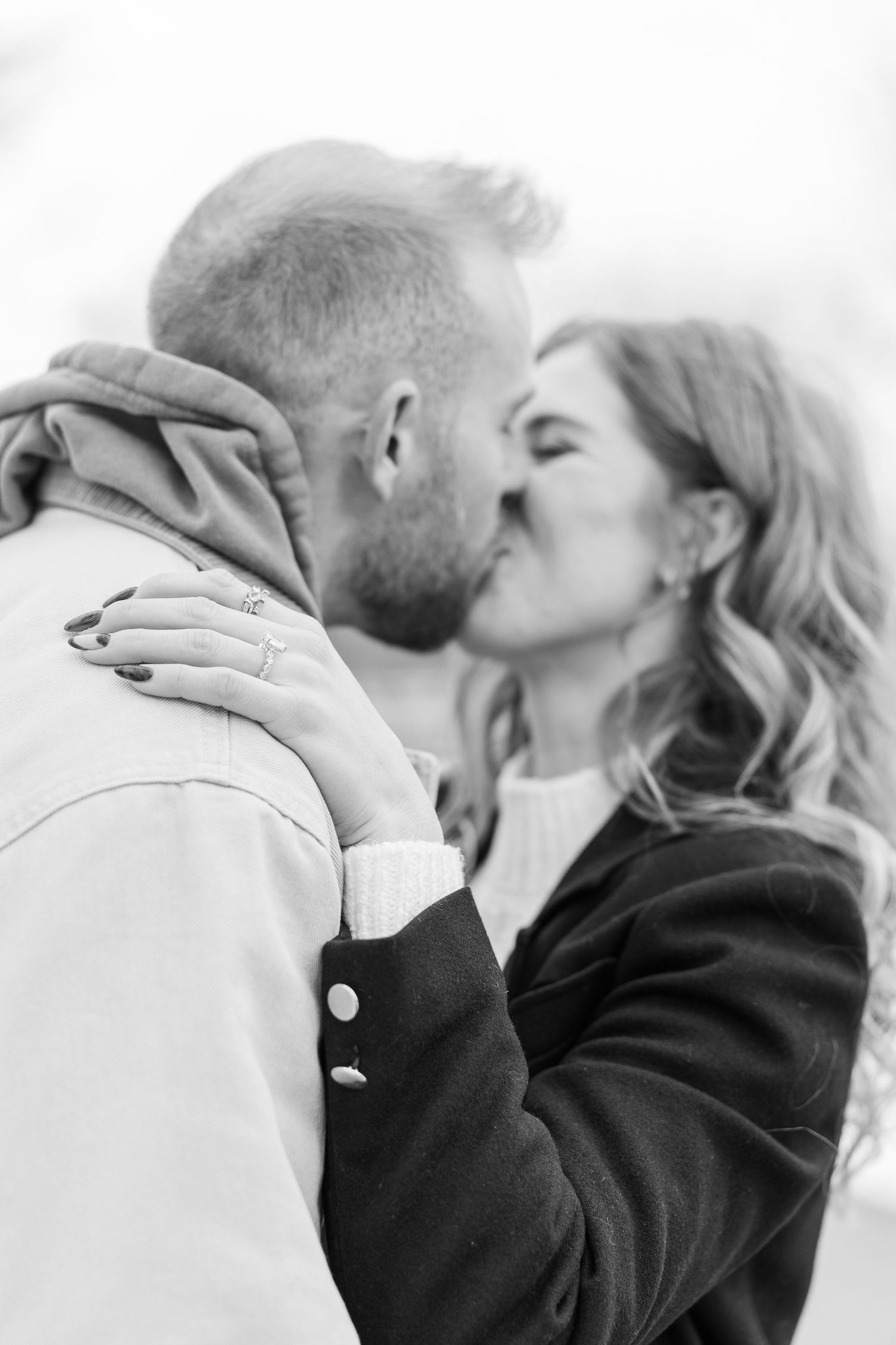 Black and white romantic photo of a couple sharing an intimate kiss, with her hand gently touching his face.