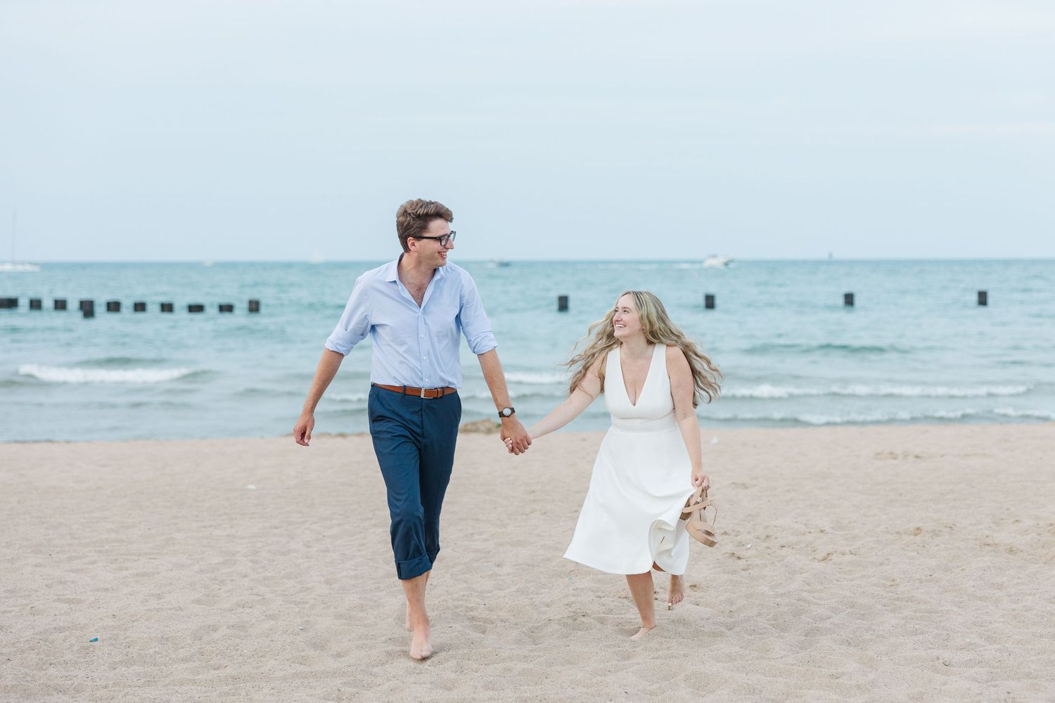 Elizabeth and Joe jogging hand-in-hand along North Avenue Beach, with gentle waves and a soft sunset in the background