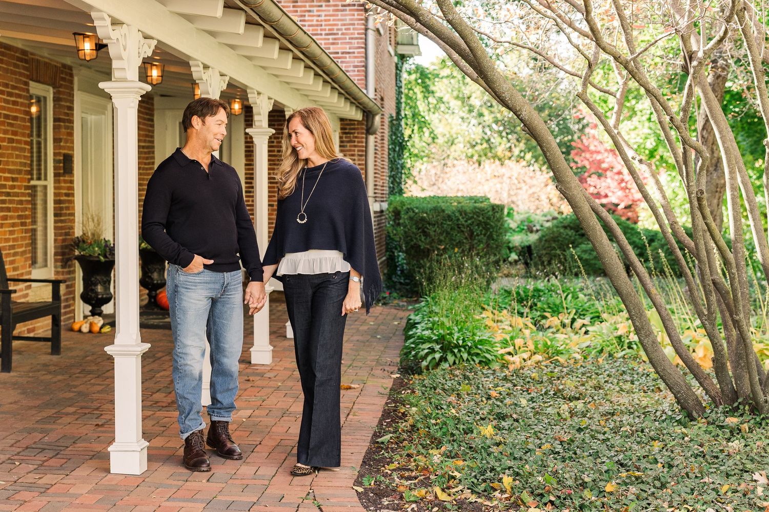 Couple strolling along brick walkway beneath white colonial-style columns.