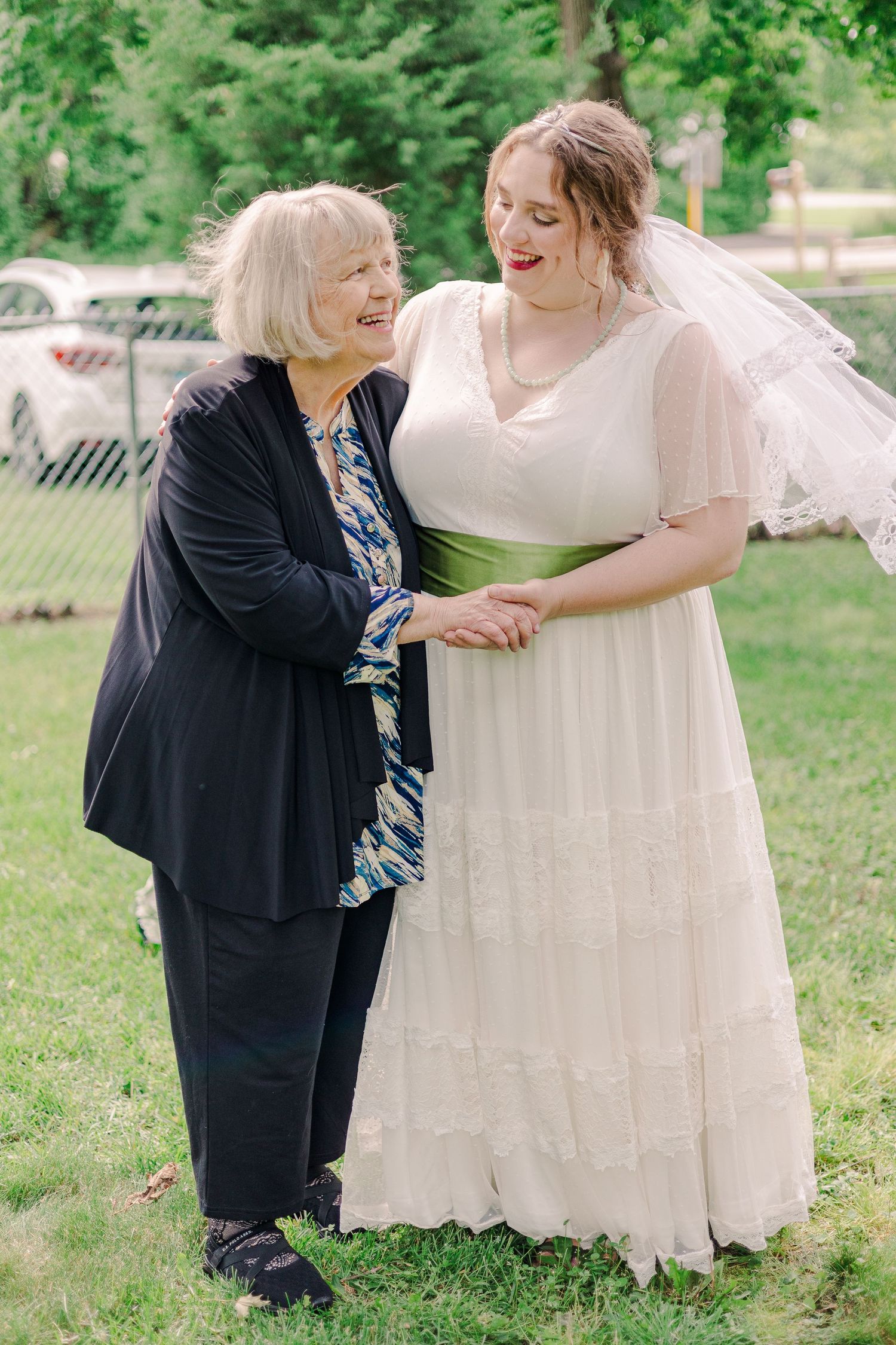 Two people share a joyful moment together on a grassy lawn during a wedding celebration.