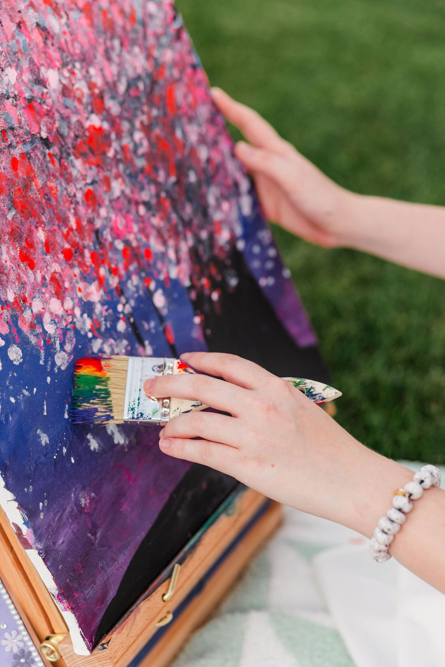 Close-up of Samantha finger-painting her colorful canvas during her creative senior portrait session at Cantigny Park.
