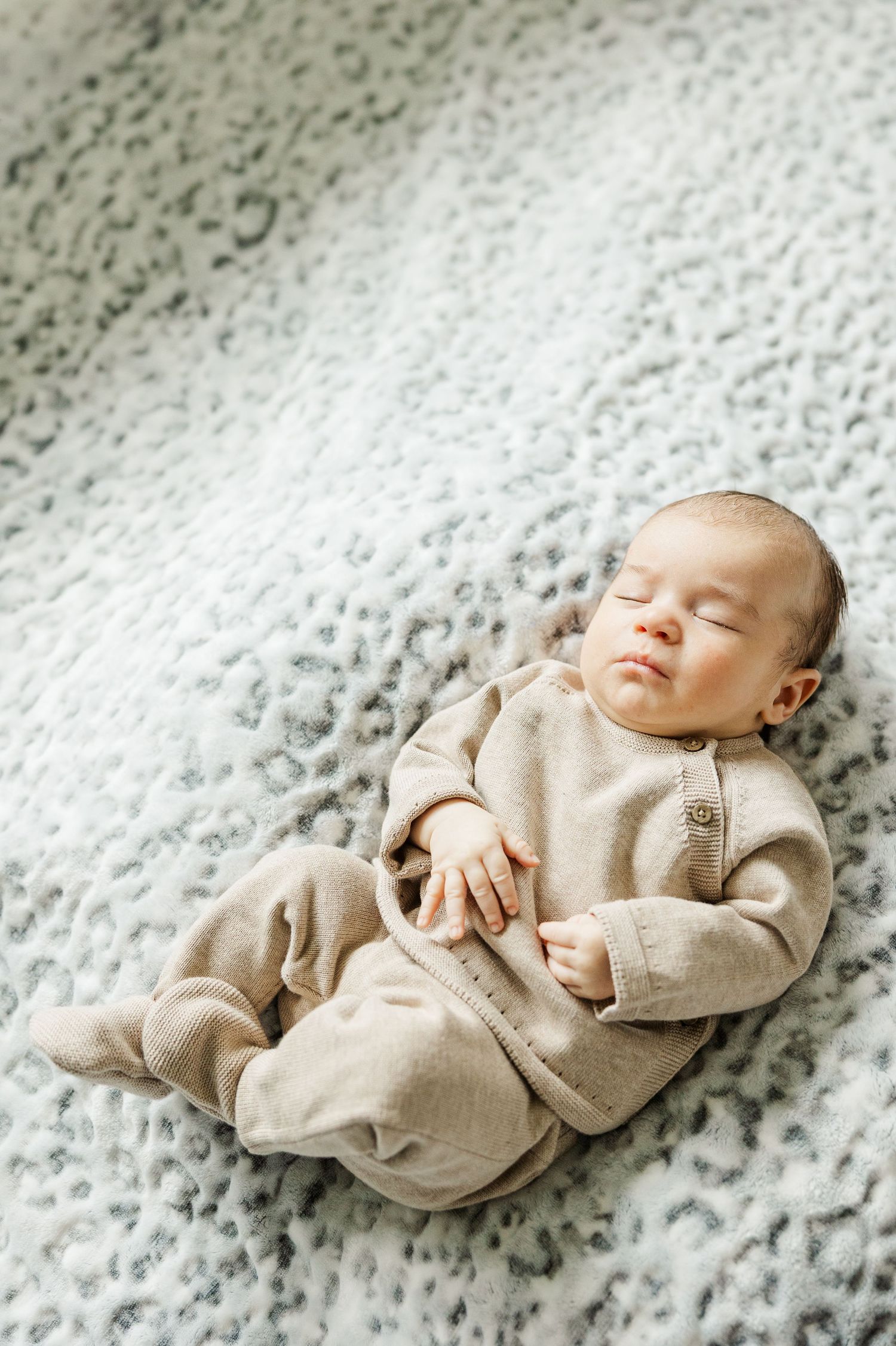 Sleeping newborn in neutral knit outfit photographed during an in-home lifestyle newborn session in Palatine IL