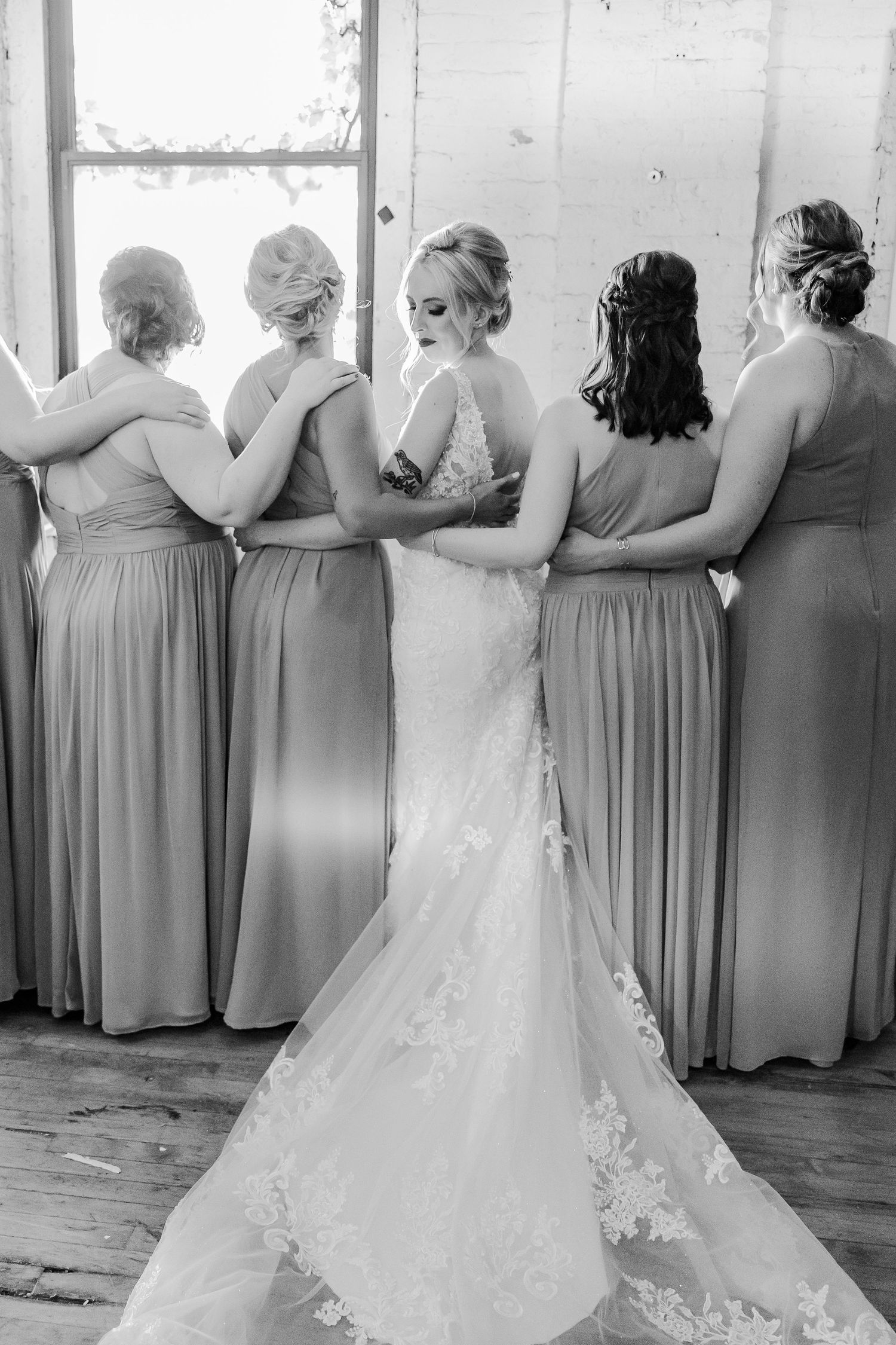 Black and white portrait of bridal party standing in line facing away from camera.