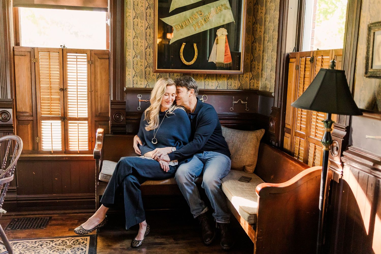 Couple sharing an intimate moment on an antique bench in a warmly lit room.