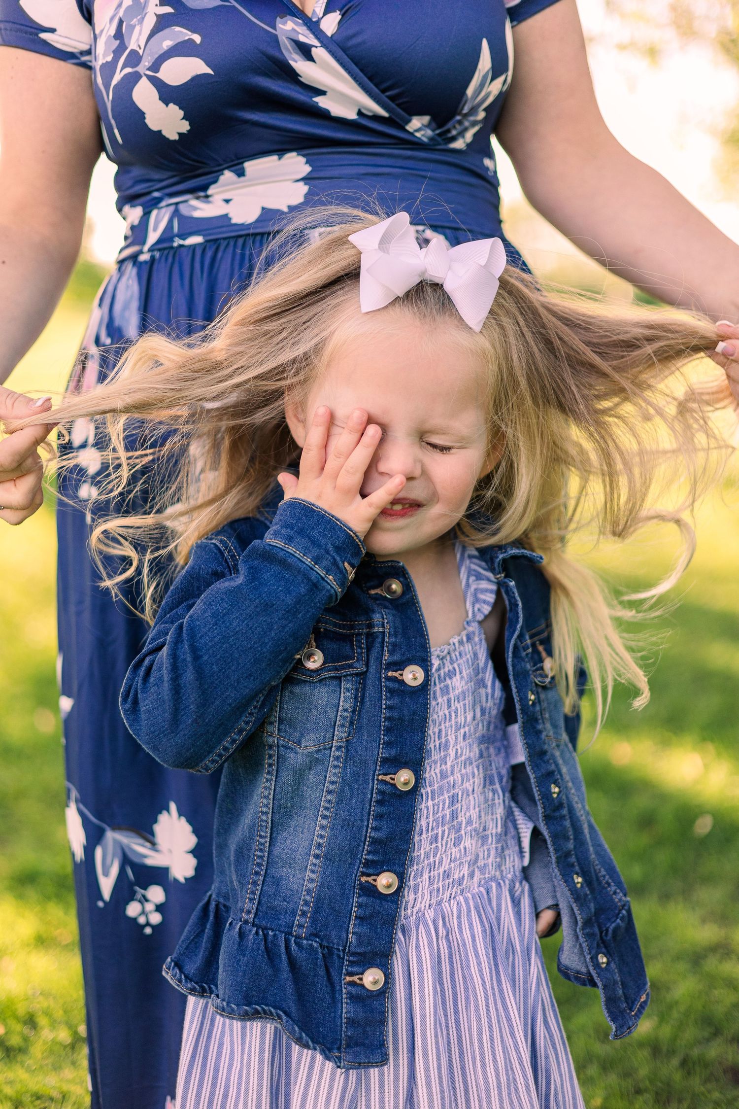 Candid laughing moment captured outdoors wearing blue denim and floral patterns.