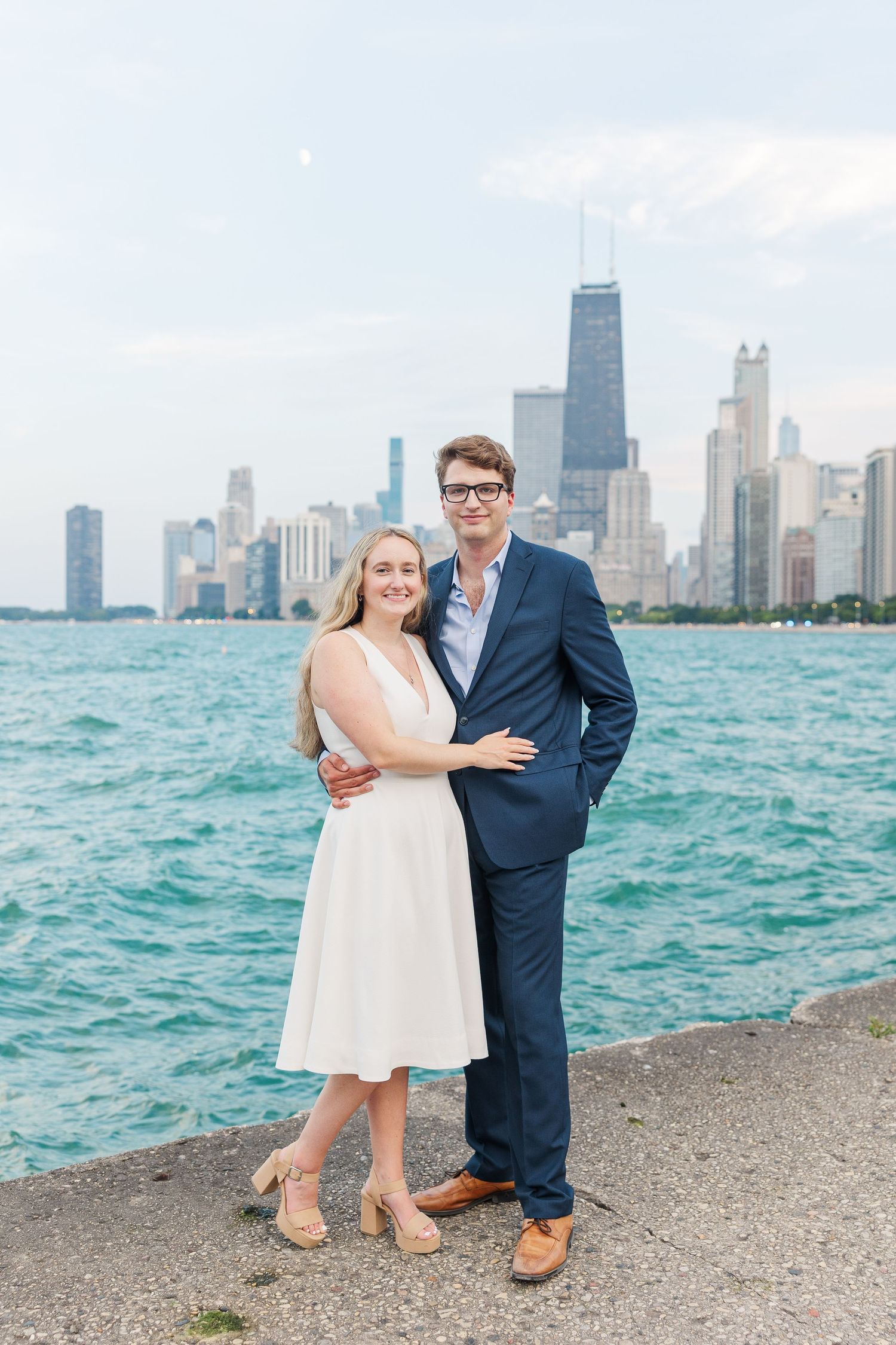Elizabeth and Joe smiling with the Chicago skyline in the background at North Avenue Beach during sunset