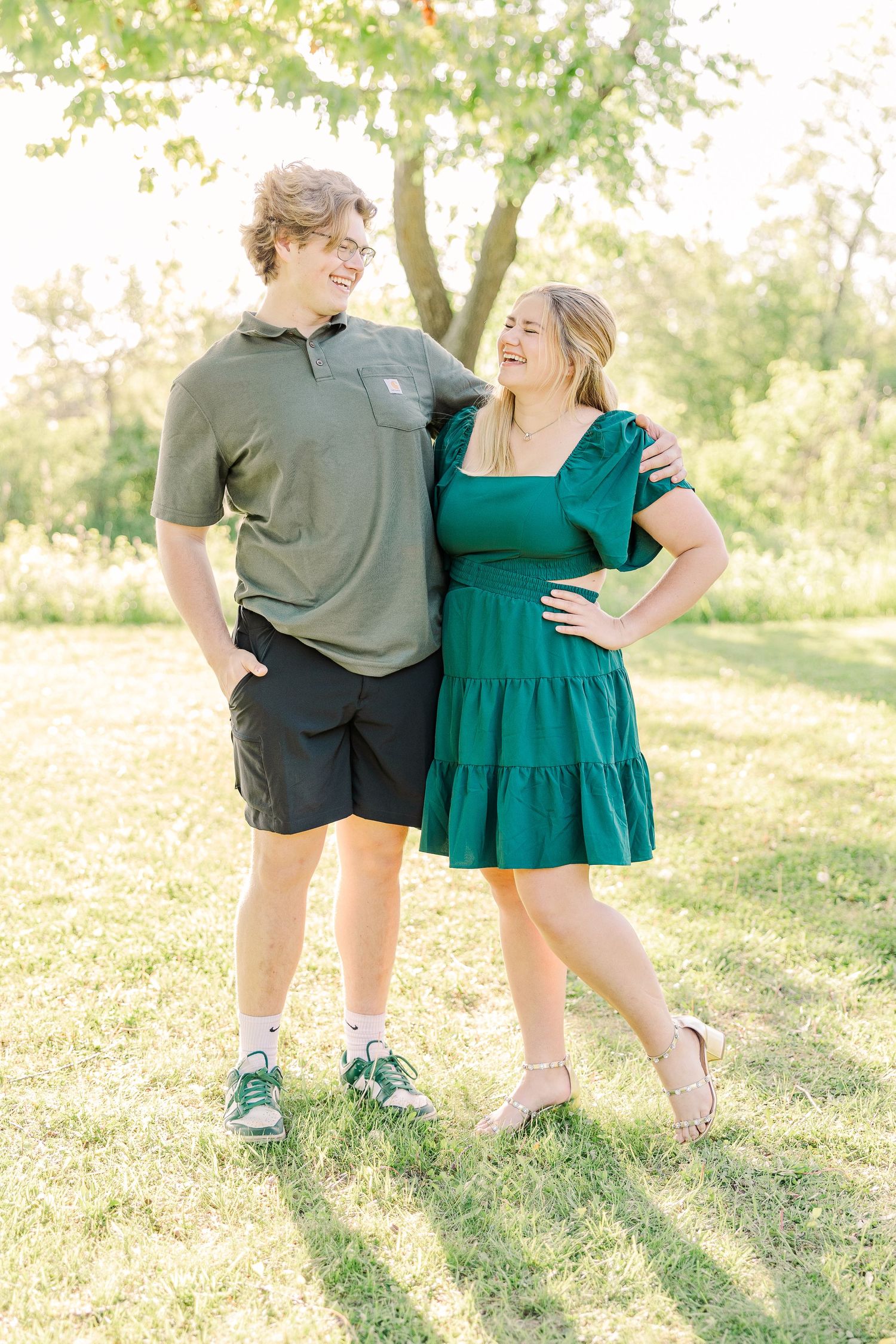 A couple sharing a joyful moment together on a sunny lawn with trees in the background.