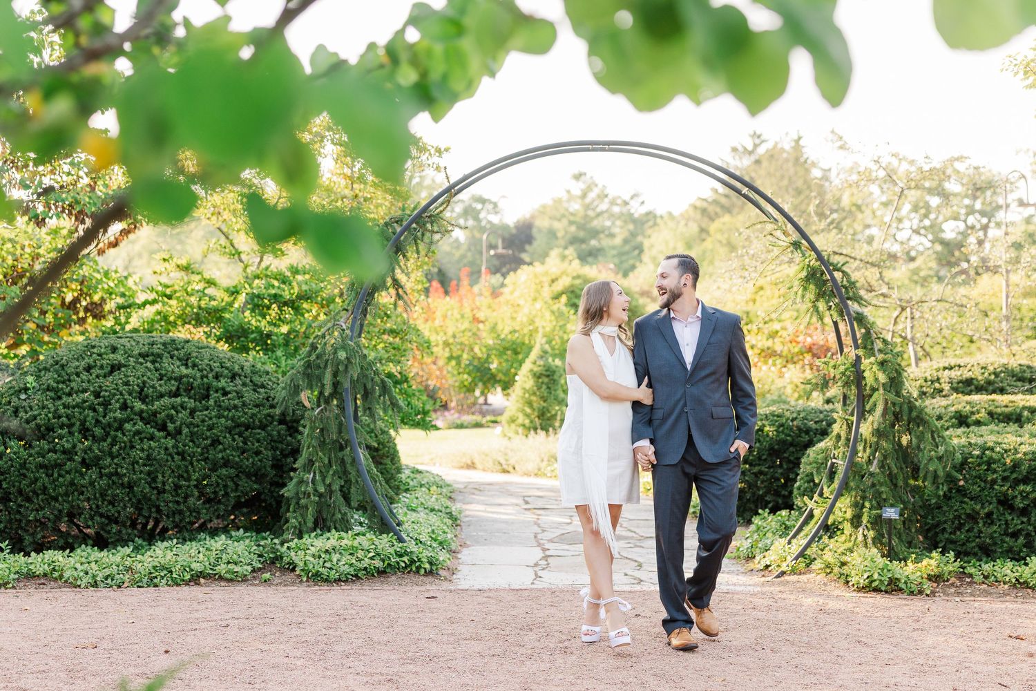 Couple walking beneath garden arch during engagement photos at Cantigny Park