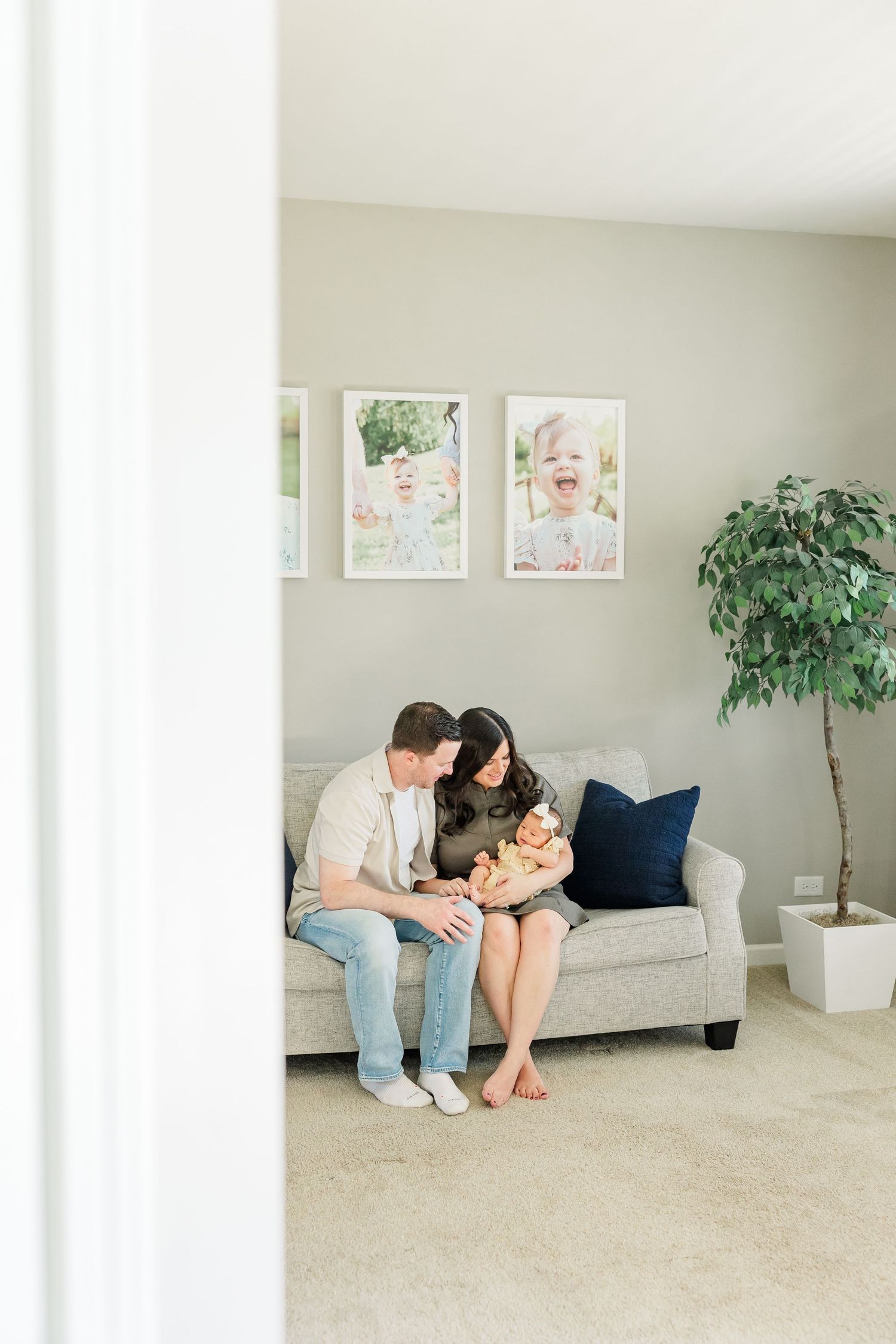 Quiet in-home newborn photo of parents snuggling baby girl together on the couch in Huntley IL