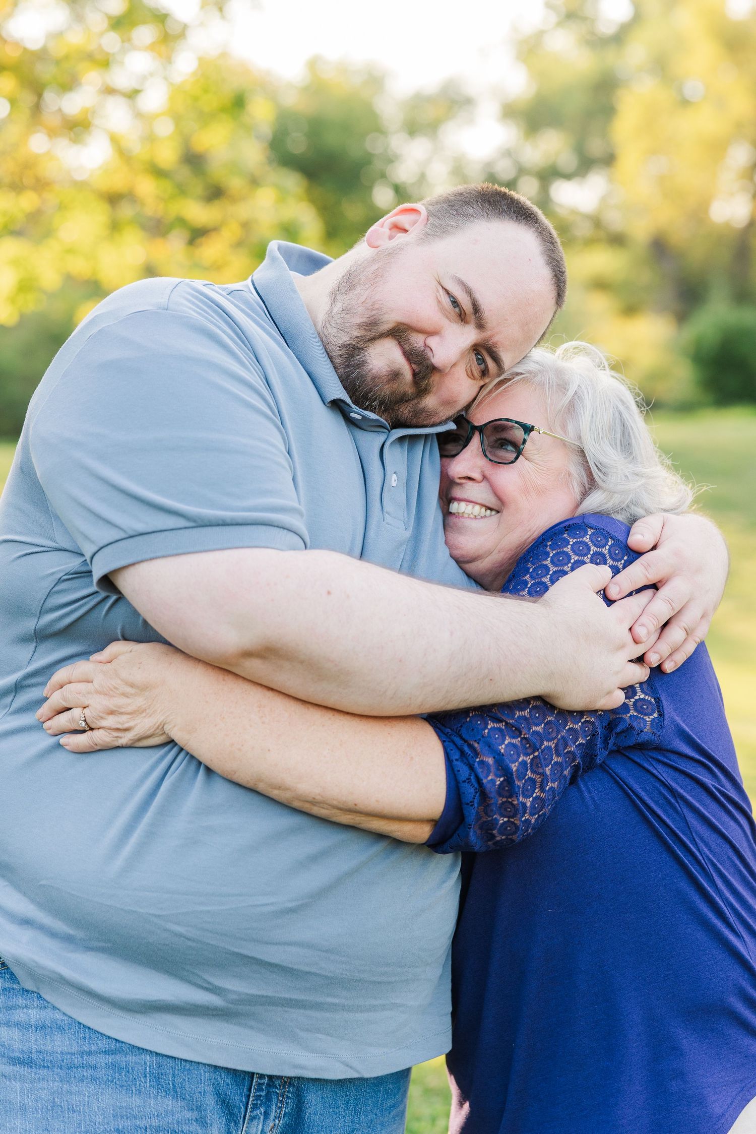 Two people share a playful and affectionate hug outdoors in a series of candid photos showing their joyful connection.Sorg family portraits