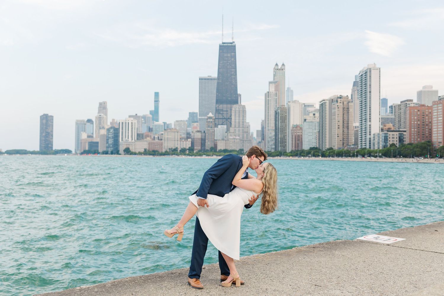 Elizabeth and Joe sharing a dip kiss with the Chicago skyline in the background at North Avenue Beach during sunset