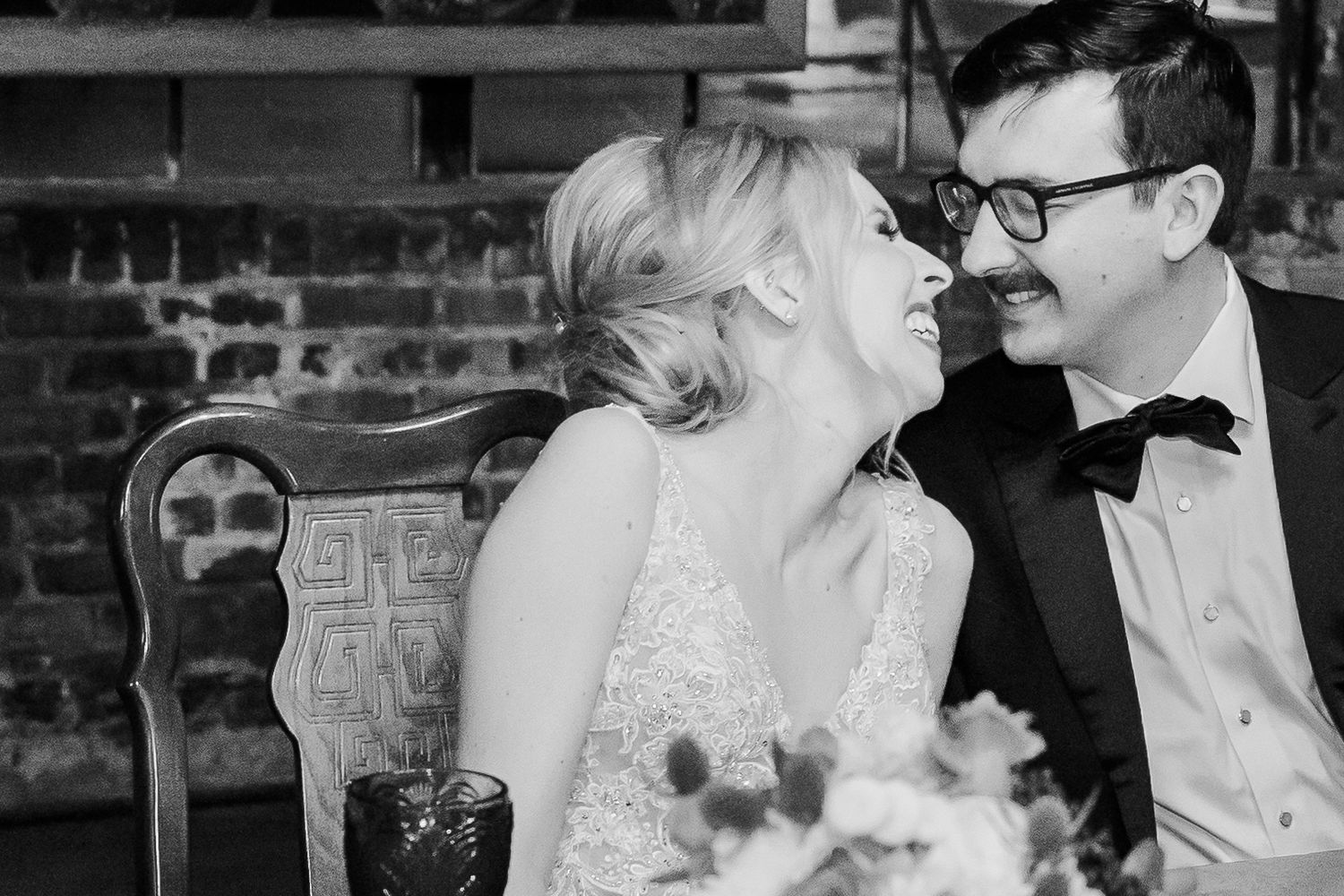 Intimate wedding reception moment captured in black and white at rustic venue.
