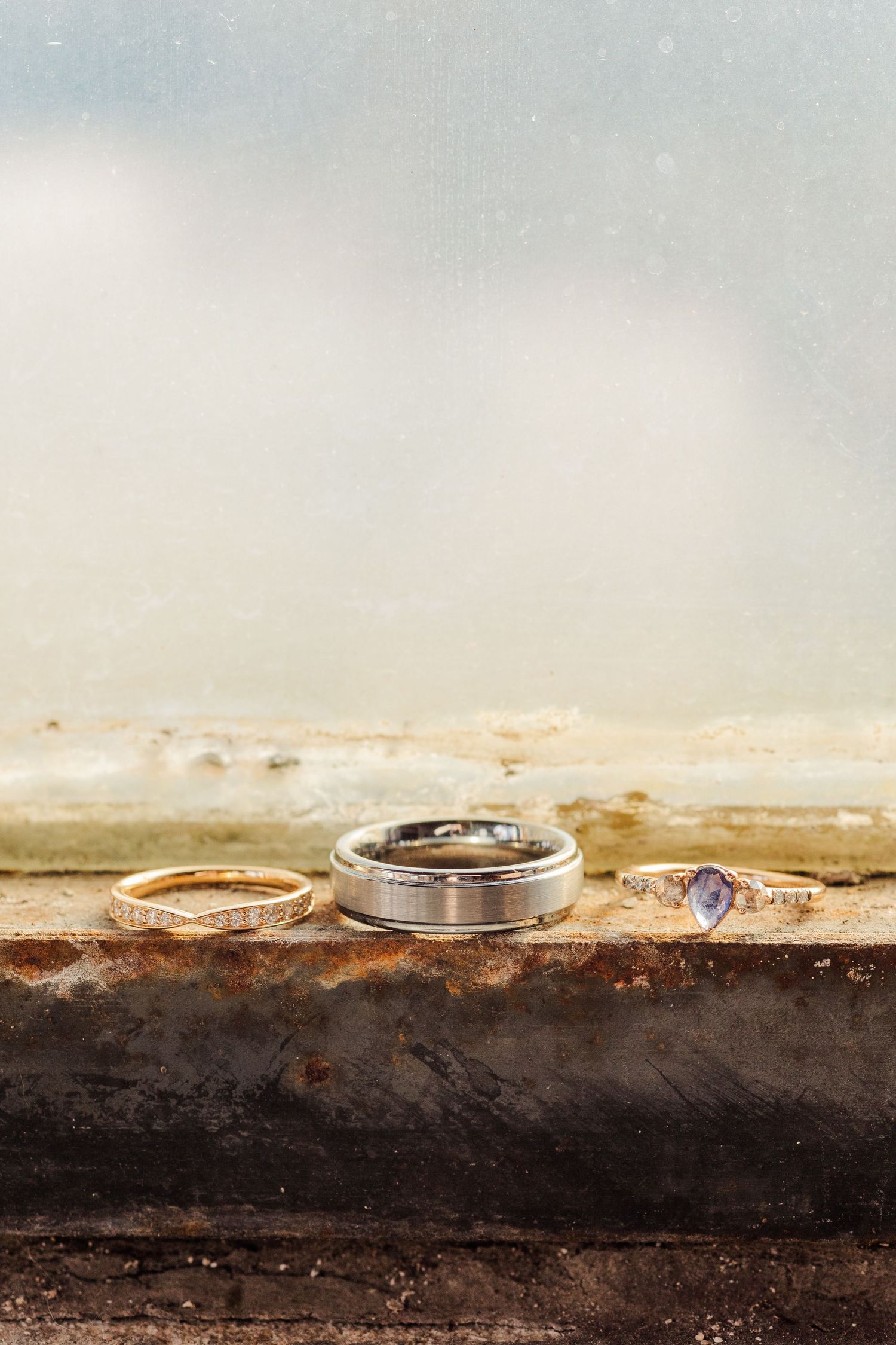 Three wedding rings arranged on a weathered wooden surface against a misty background.