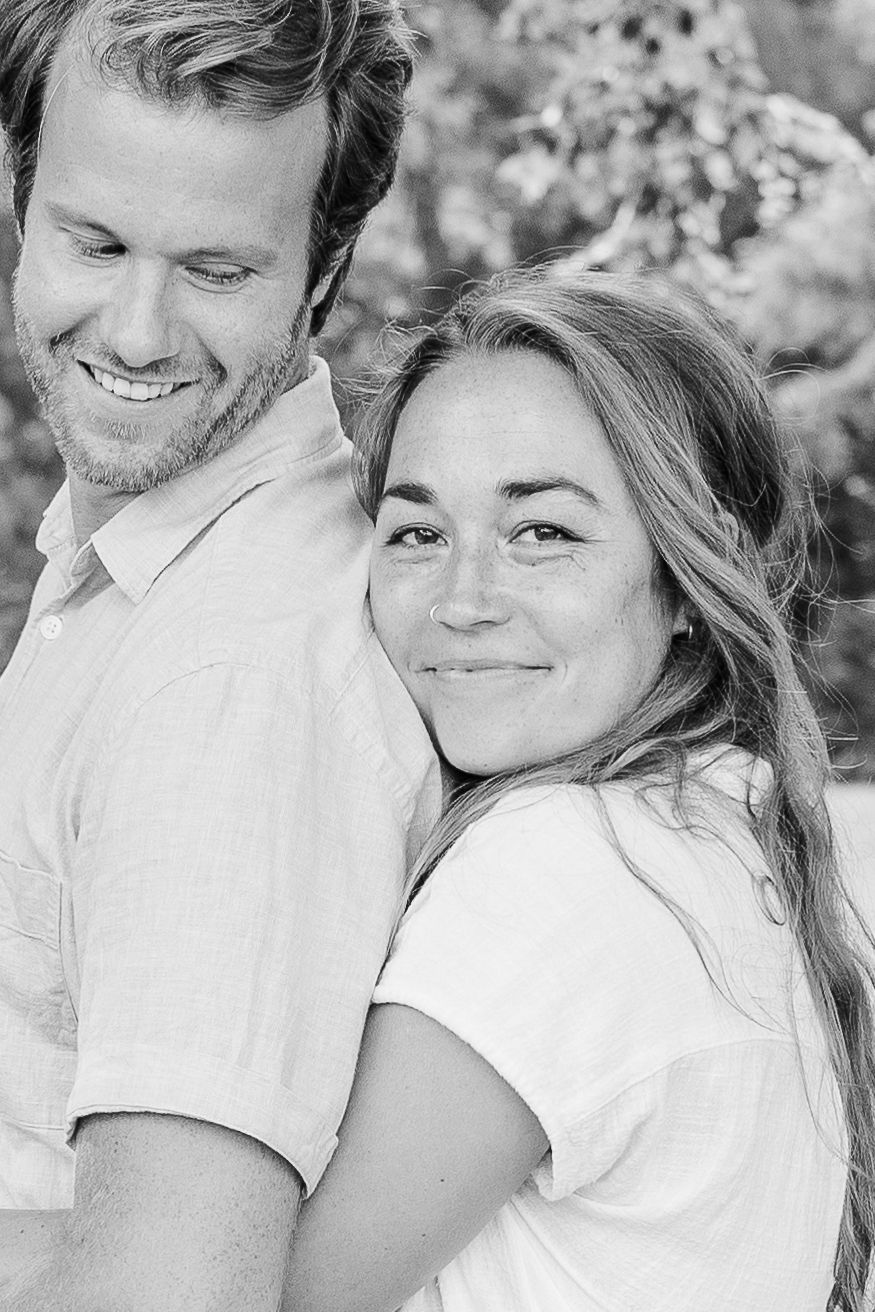 A black and white portrait of a happy couple smiling and embracing outdoors.