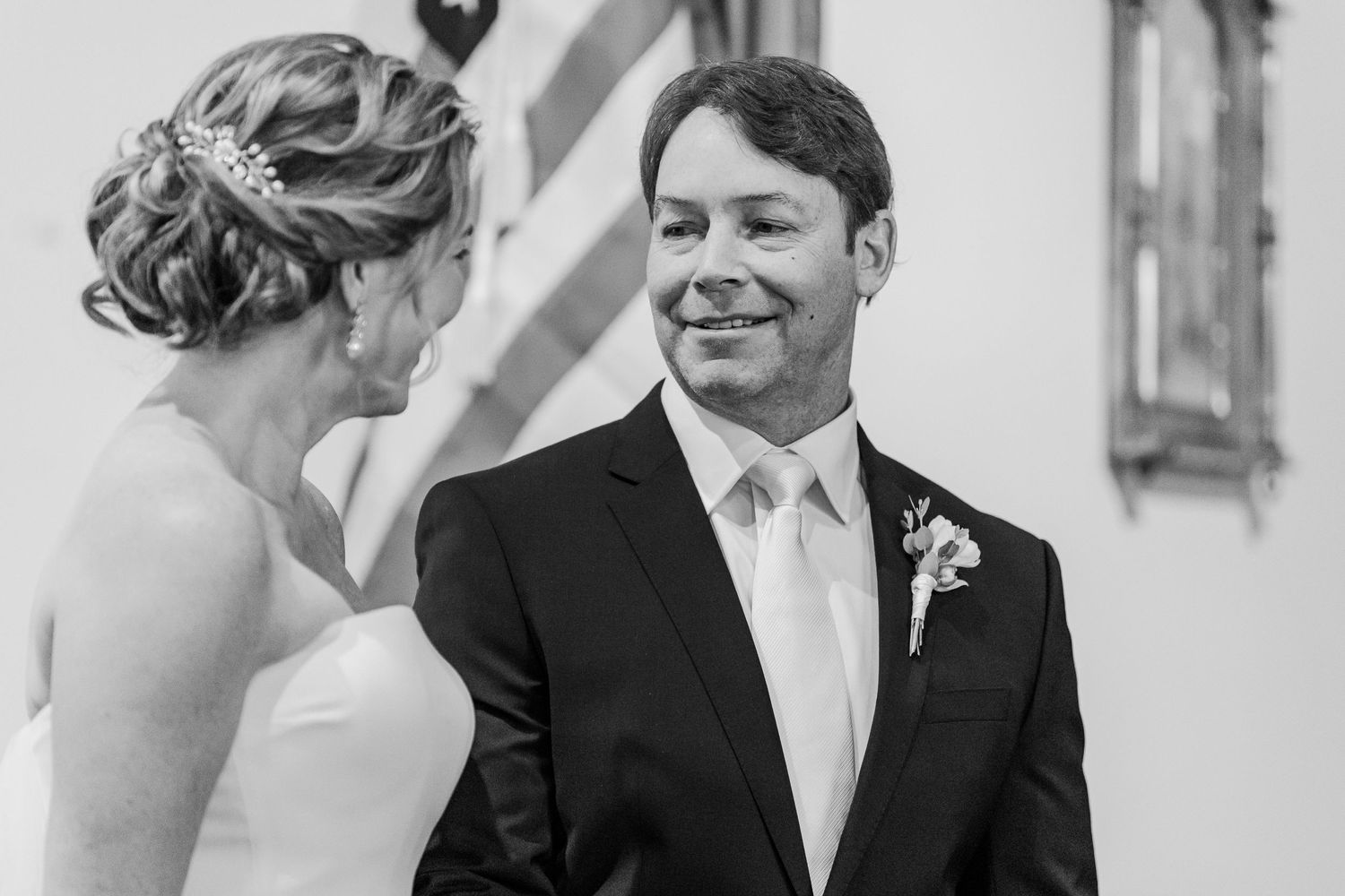 A black and white candid moment of joy shared between newlyweds during their church ceremony.