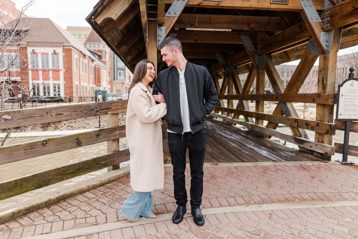 A couple shares a sweet moment while standing together on a covered bridge walkway.