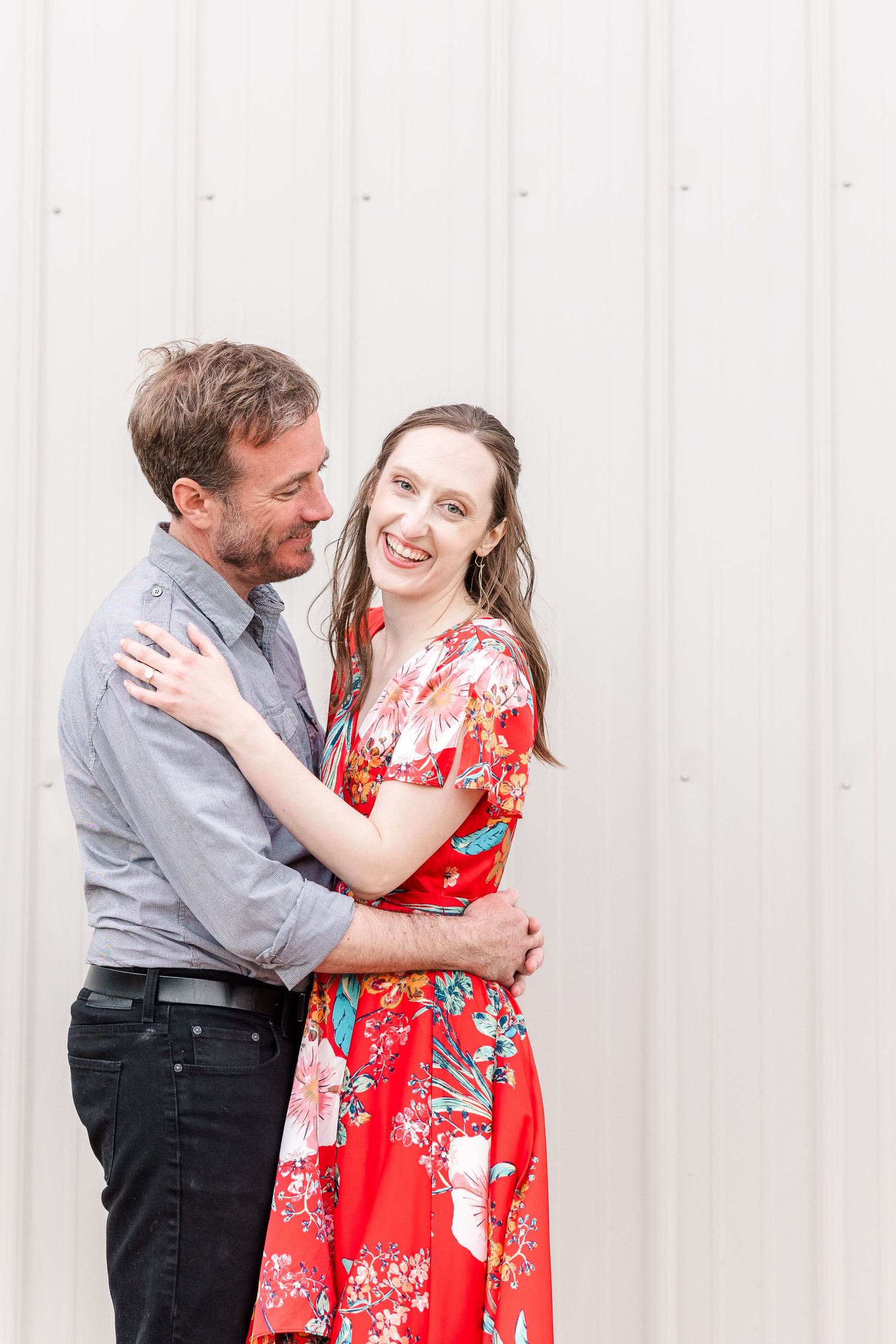 Couple sharing a joyful moment against a white wall background.