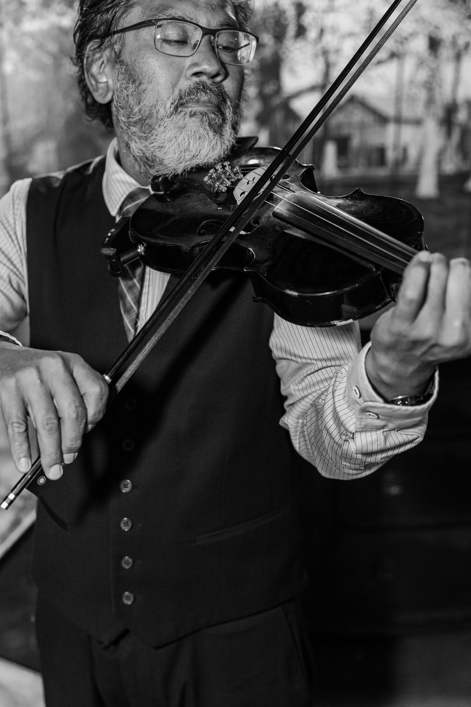 Close-up of bearded musician playing violin in formal attire.
