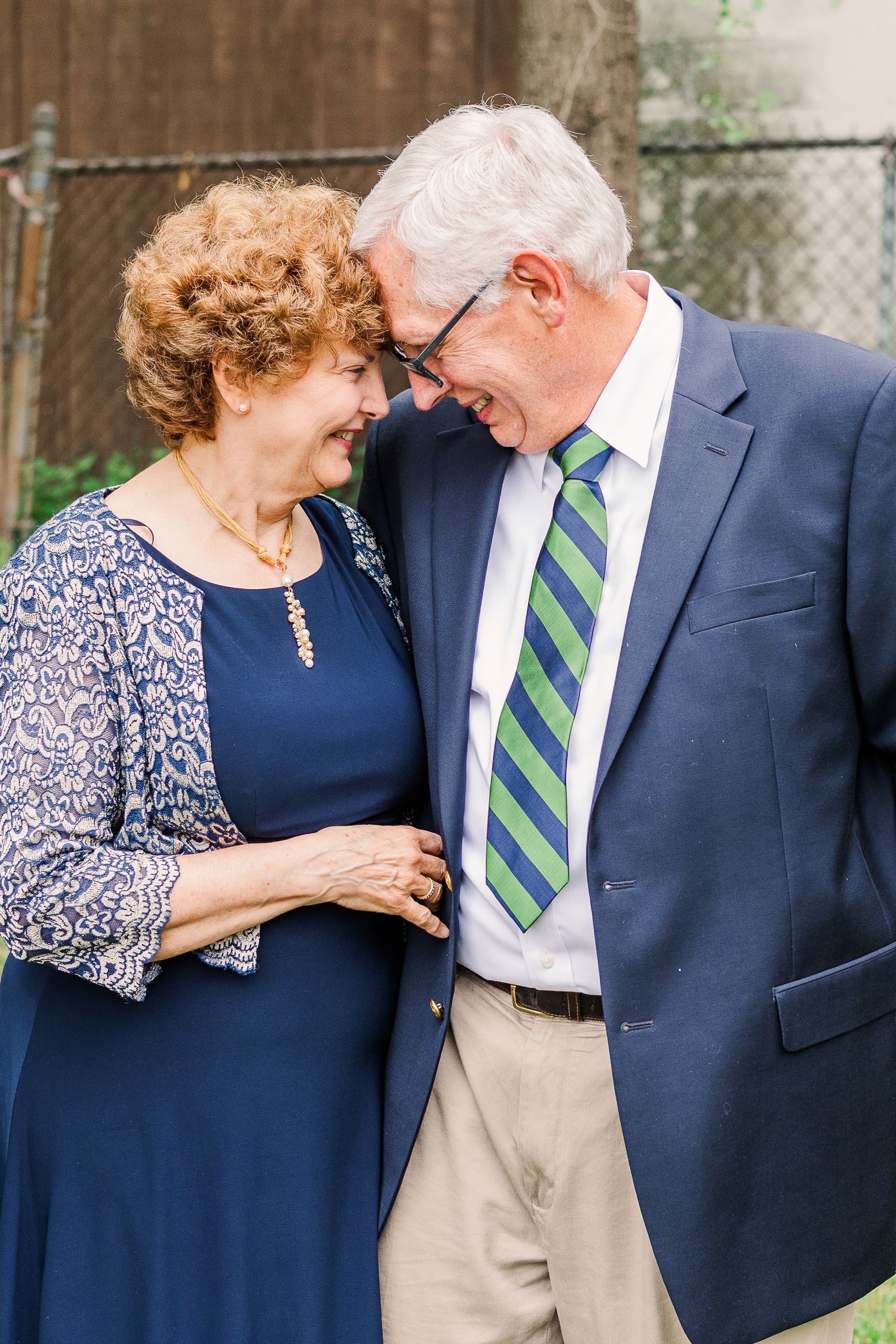 An older couple shares an intimate moment wearing formal attire at an outdoor event.